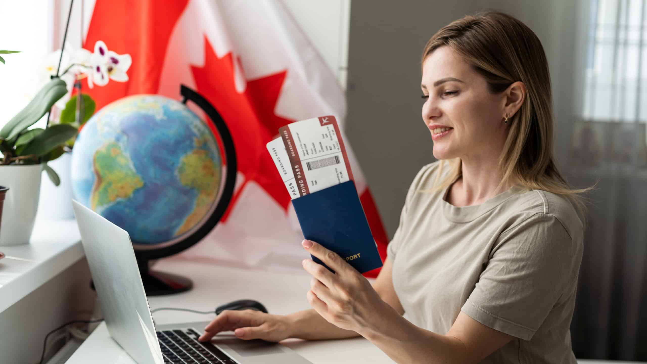 beautiful smiling woman covered in canadian flag looking at camera isolated on white