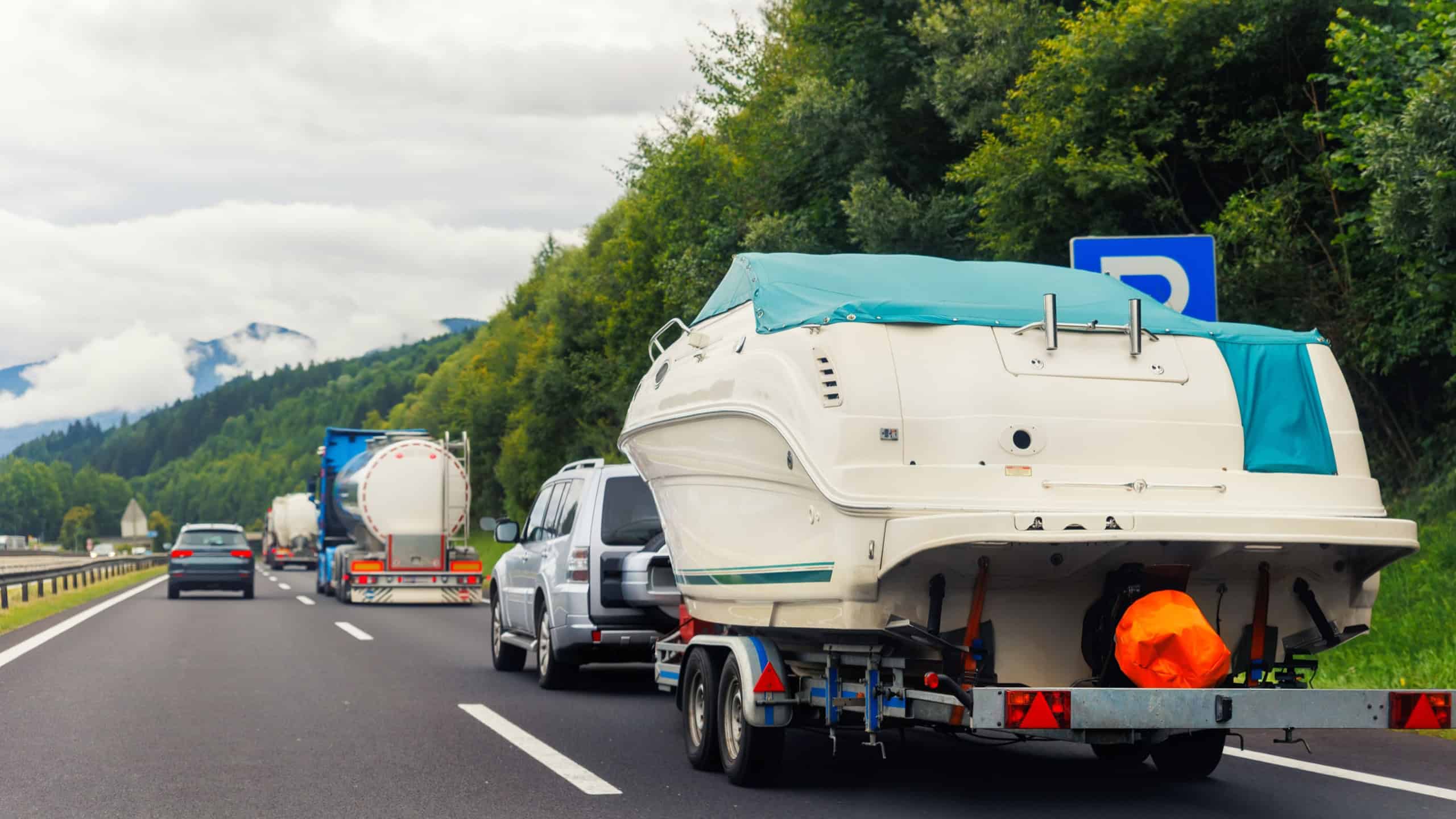 Modern luxury SUV towing yacht boat trailer carrier go river lake sea vacation mountain highway road summer light. Luxury rich fishing leisure recreation lifestyle. Service maintenance transportation