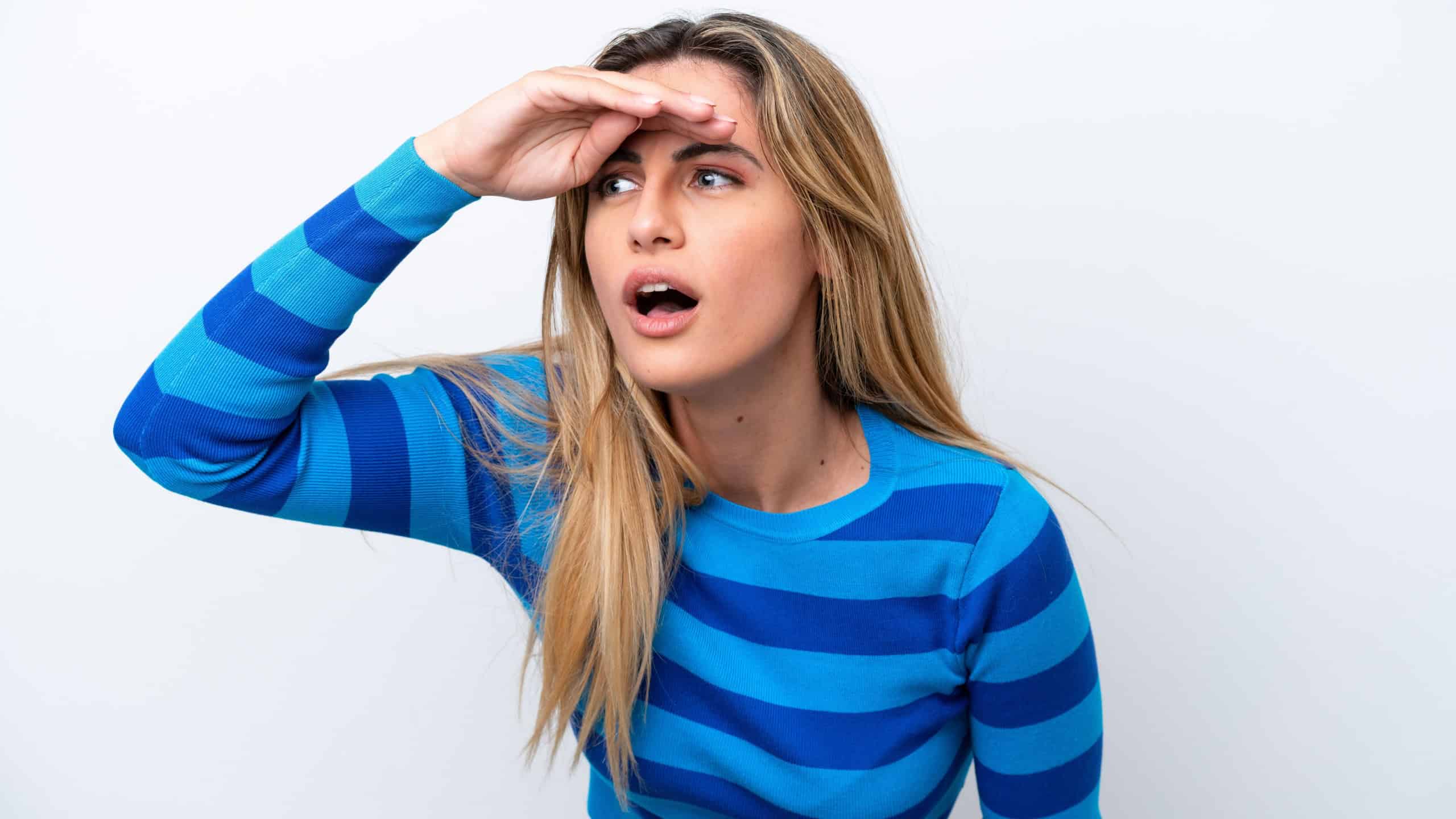Young caucasian woman isolated on white background looking far away with hand to look something