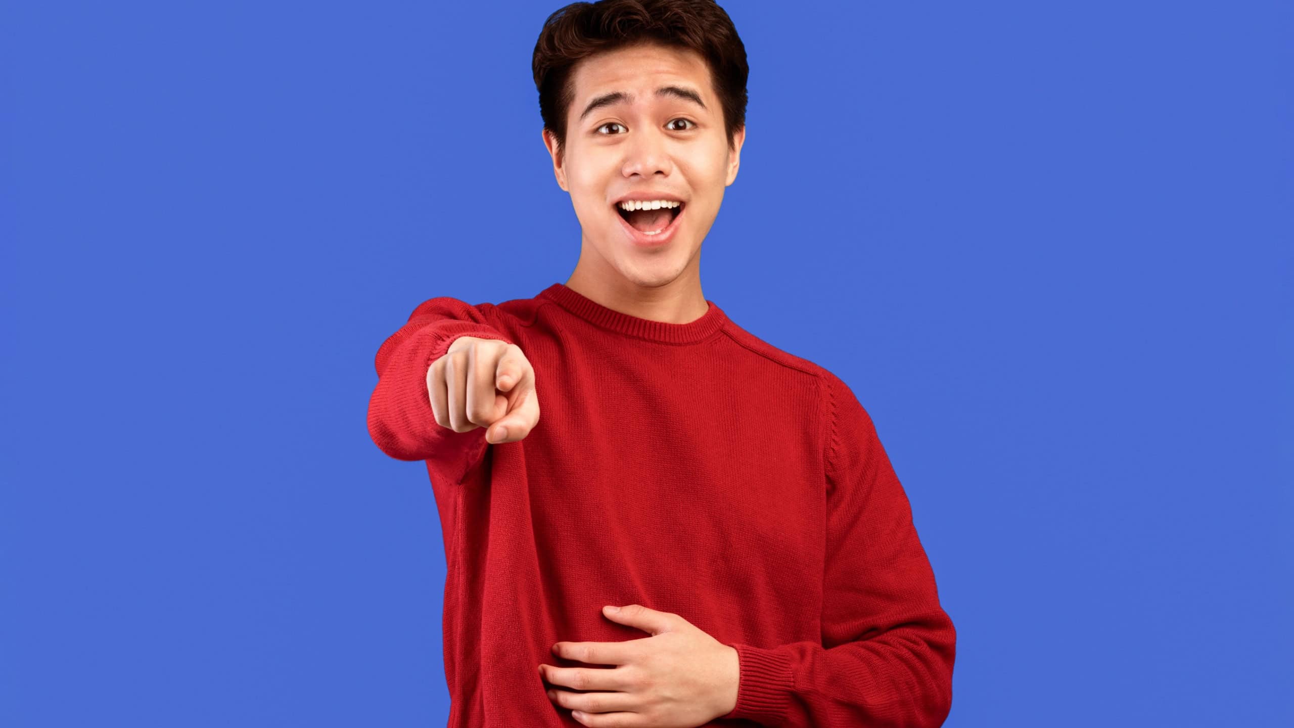 Young handsome asian man laughing at you