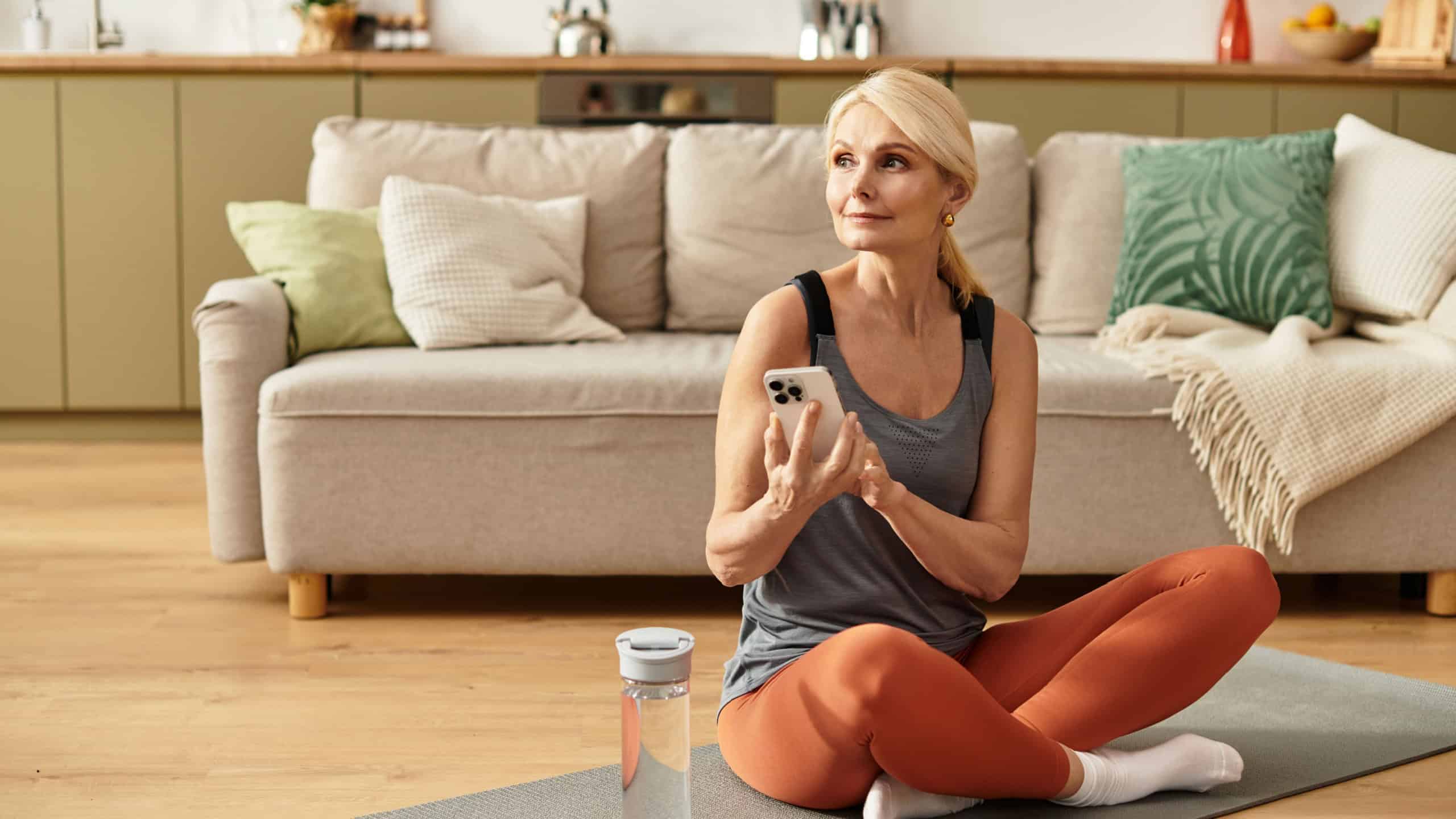 Beautiful senior woman practices mindfulness seated on a yoga mat in her inviting living room.