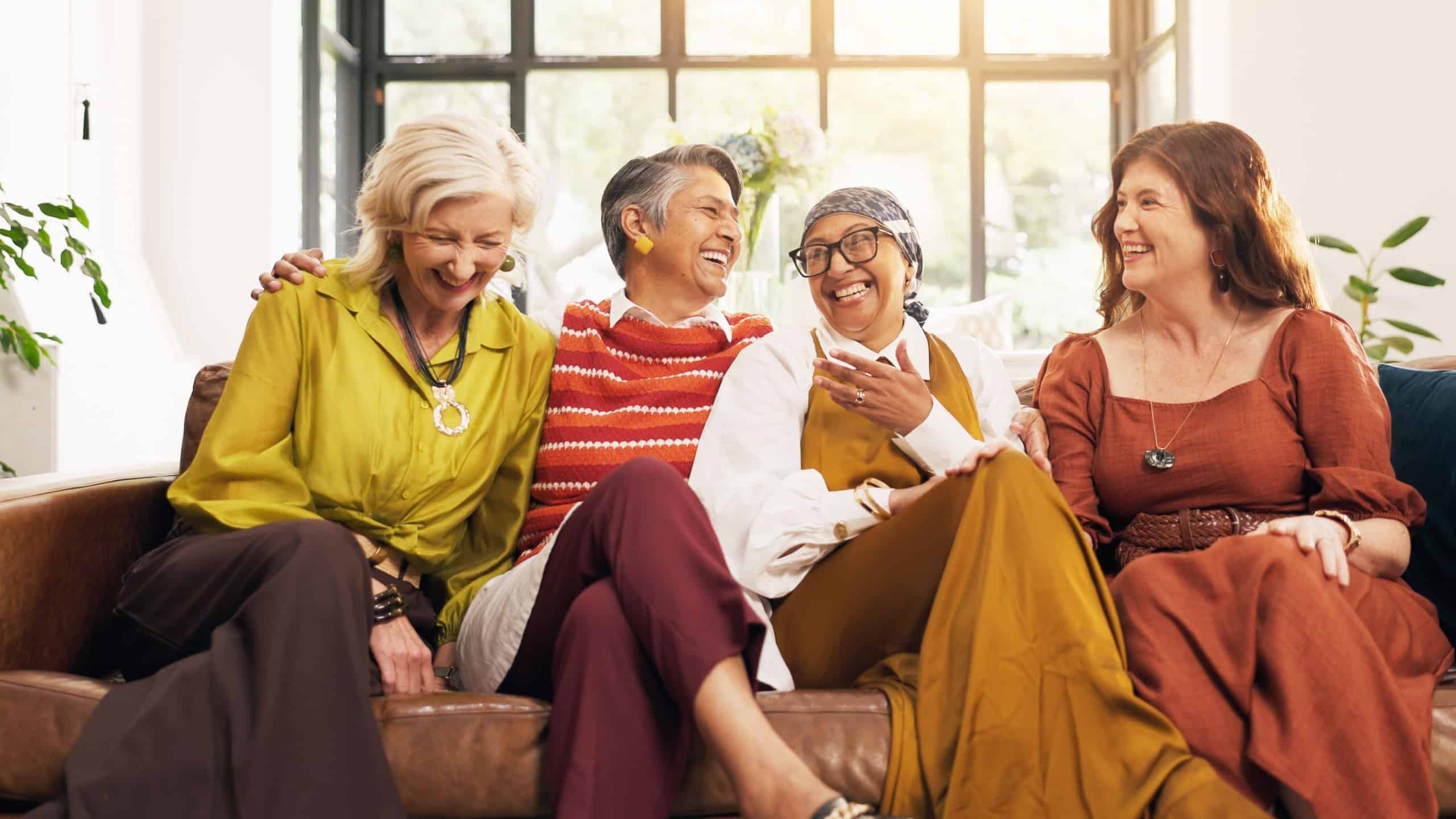 Laughing, friends and old women on couch, home and bonding with gossip in lounge, happy and reunion. Senior people, conversation and humor for funny joke in living room, relax and break in apartment