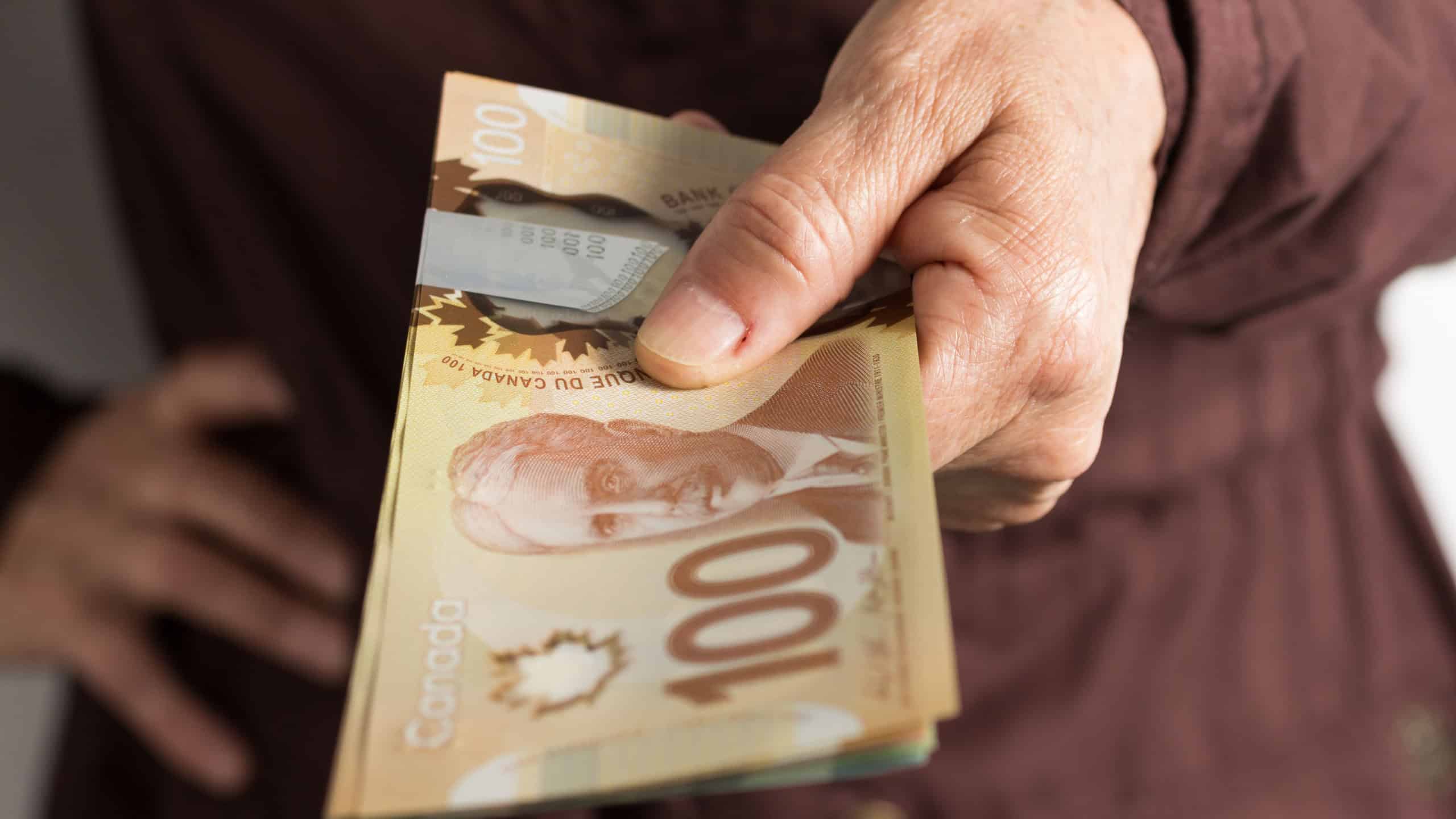 Paper notes from Canada. Dollar. Canadian cash. Front view of old woman's hand handling bills.