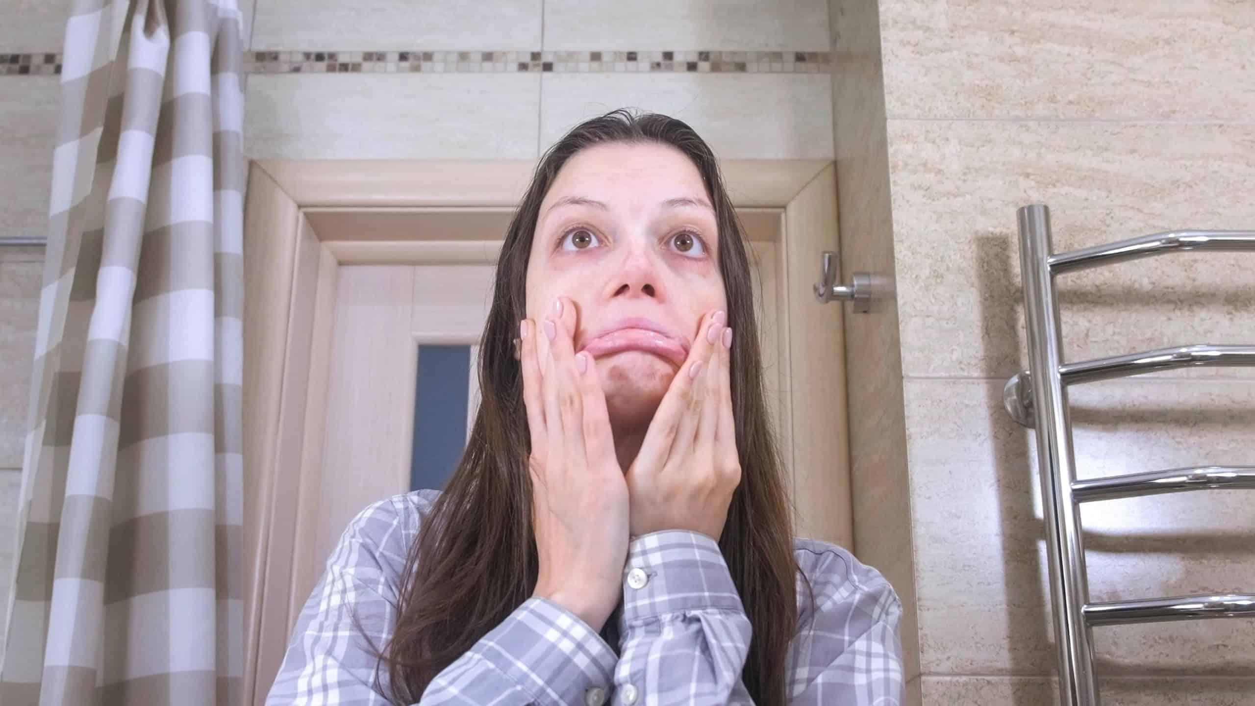 Sleepy woman who has just woken up with a hangover in the bathroom try to puts herself in order.