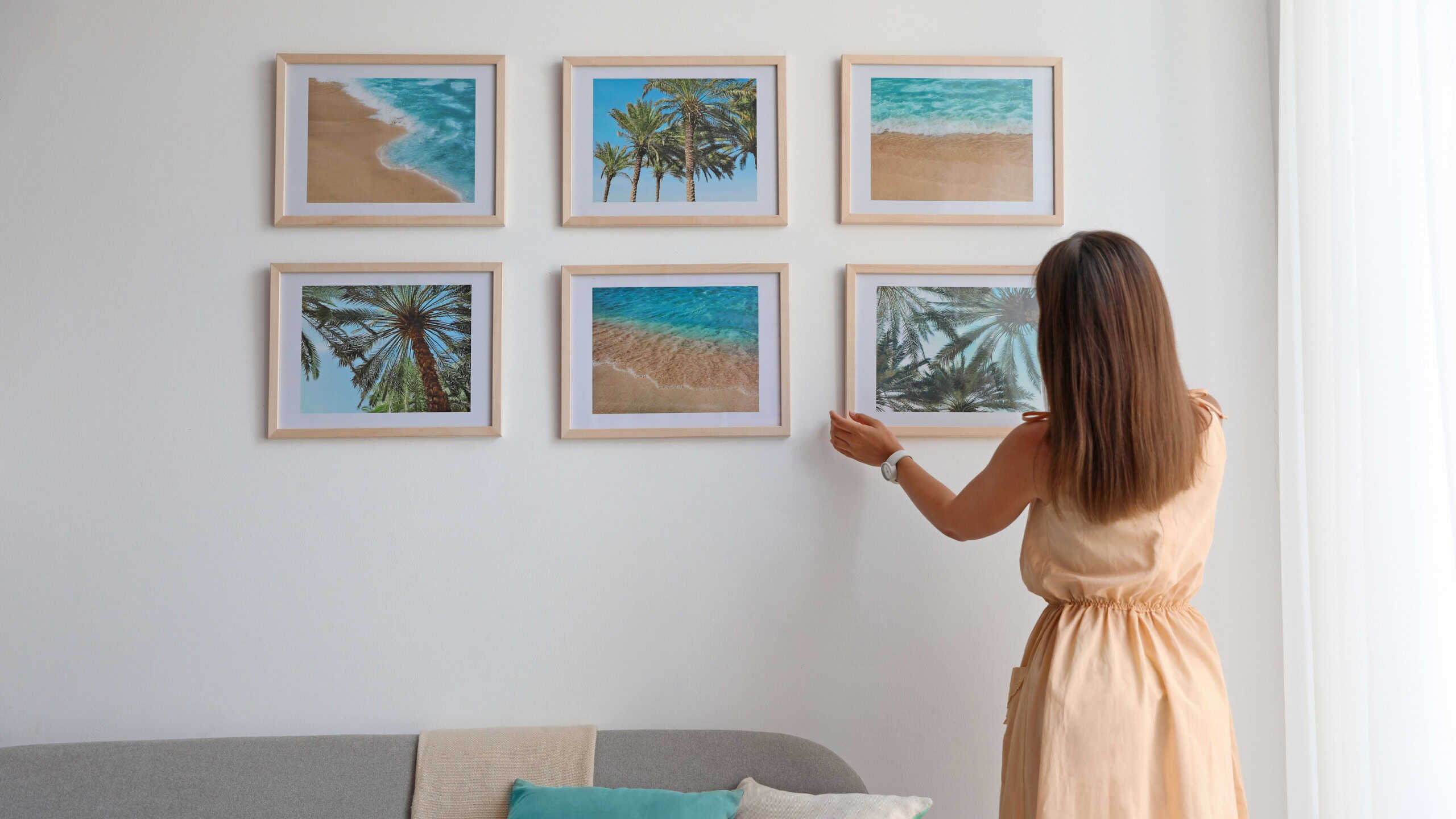 Female interior designer decorating white wall with pictures indoors