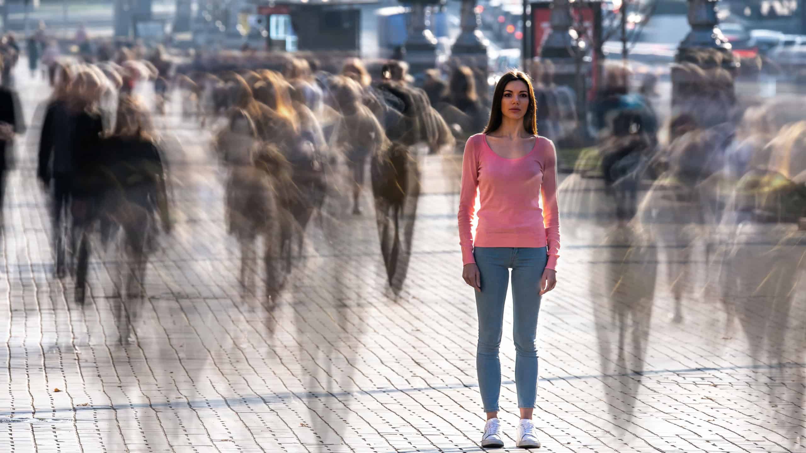 The young woman stands in the middle of crowded street