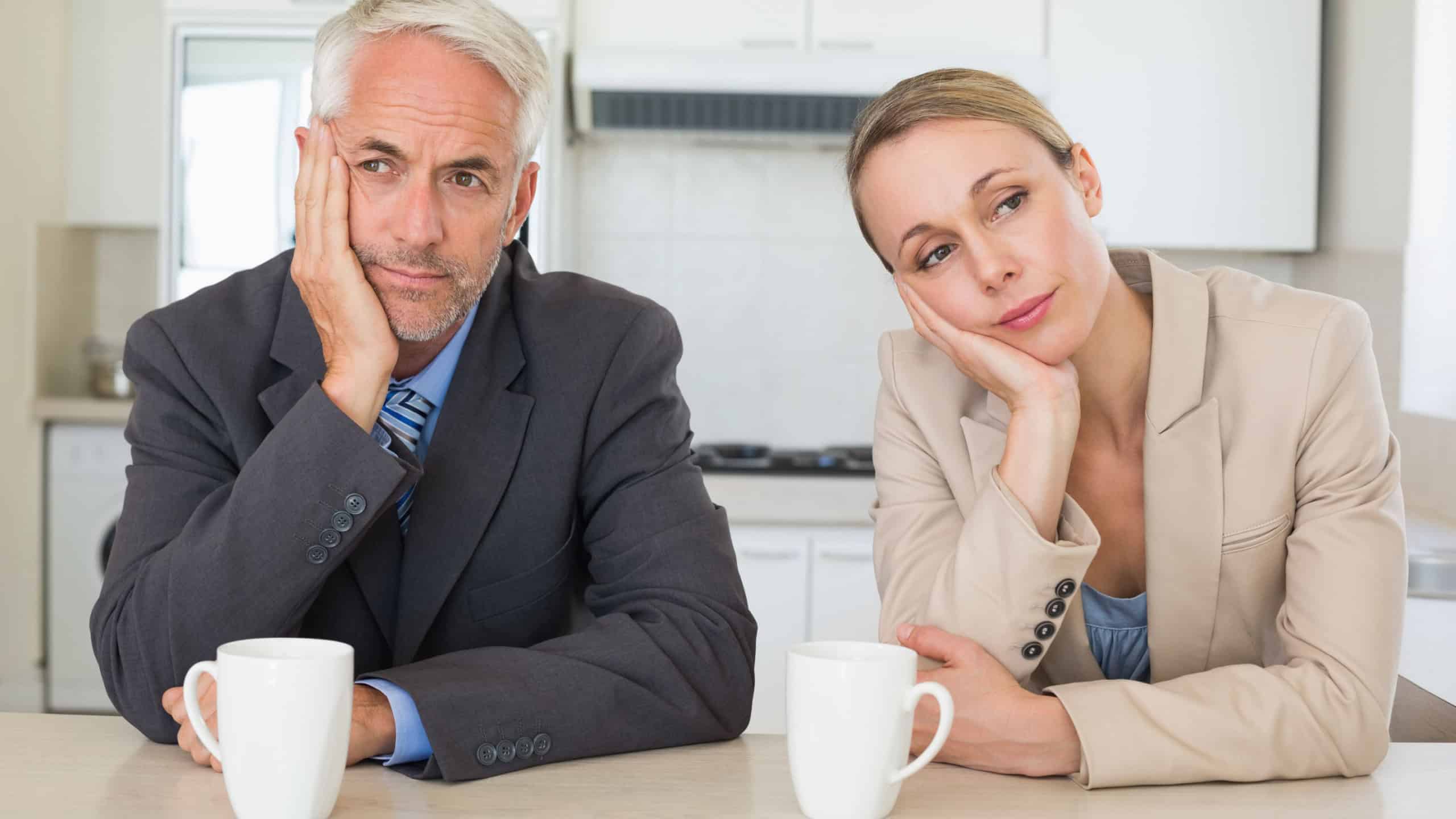 Bored business couple having coffee before work in morning at home in the kitchen