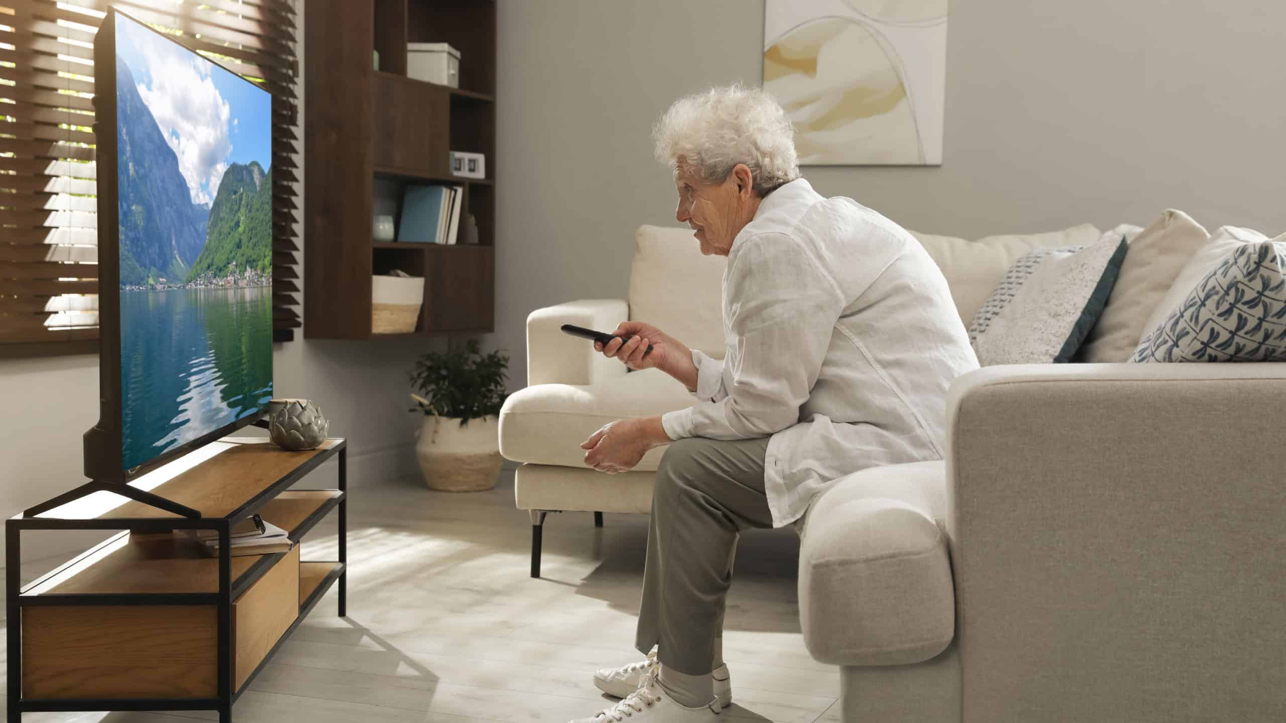 Elderly woman with poor posture watching TV in living room