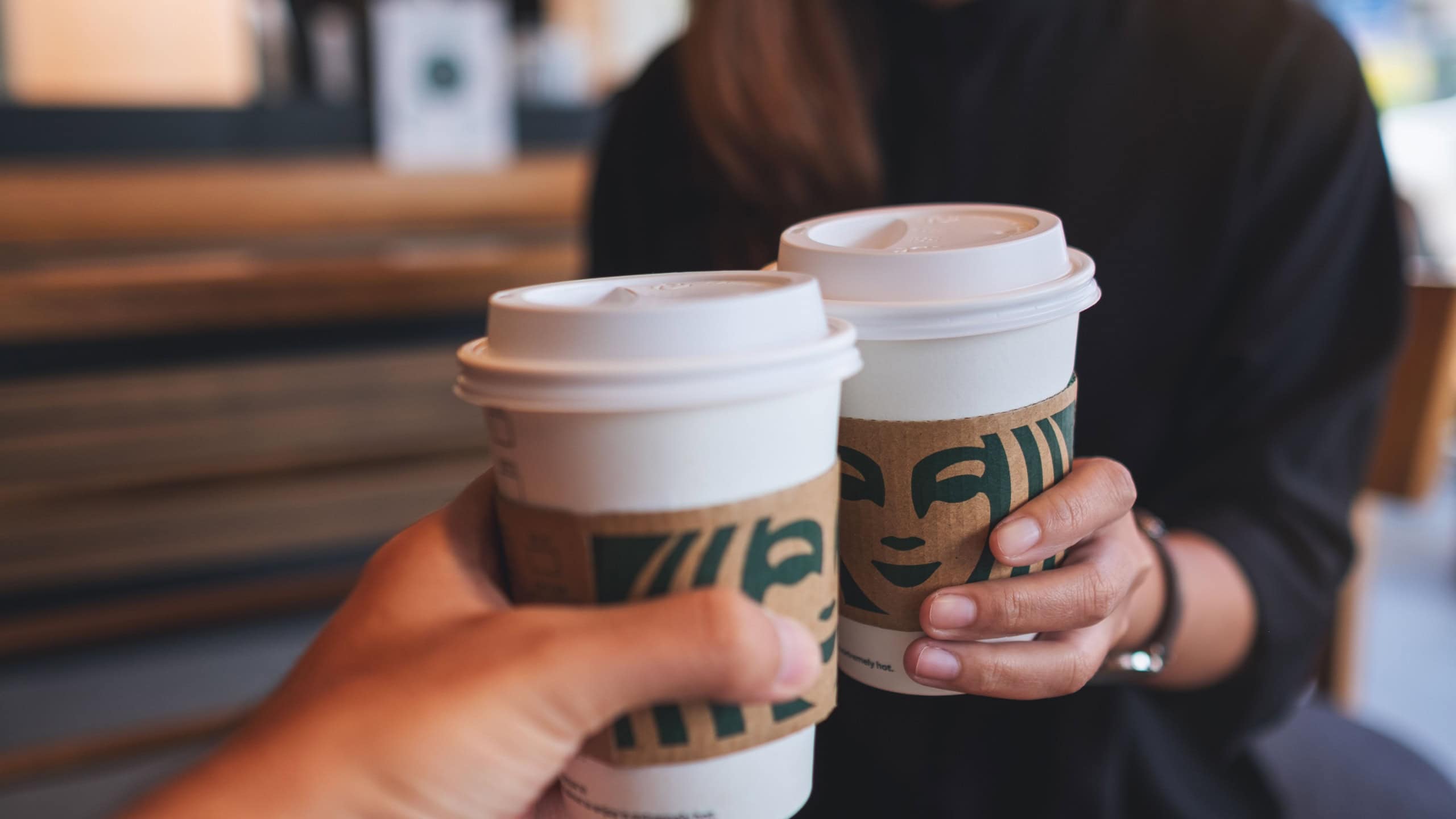 Jun 13th 2022 : Closeup of a couple people holding and clinking two cup of hot coffee at Starbucks coffee shop, Chiang mai Thailand