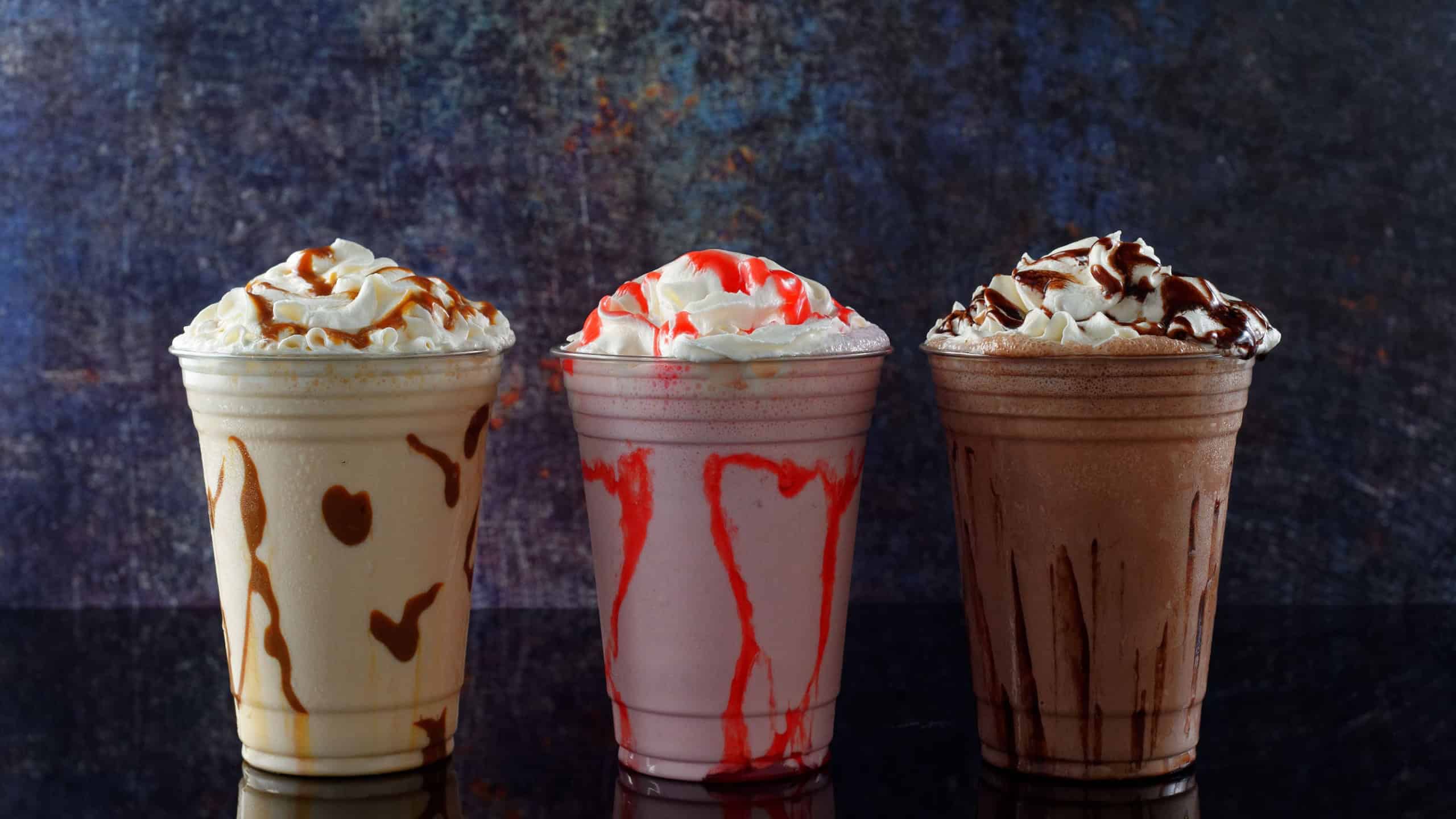 Milkshakes of different flavors on a dark background.