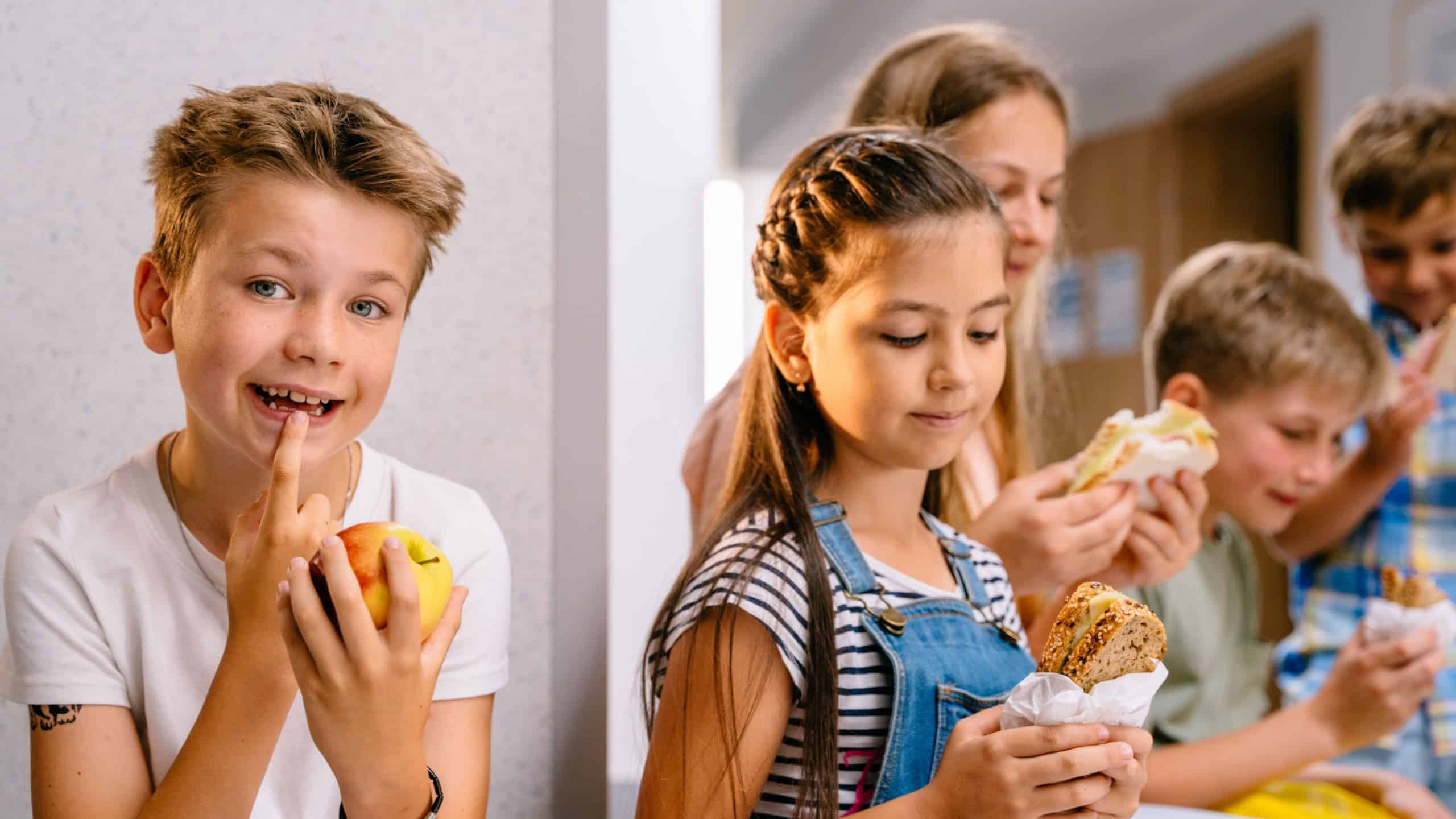 Different age pupils in school corridor during lunch break. 