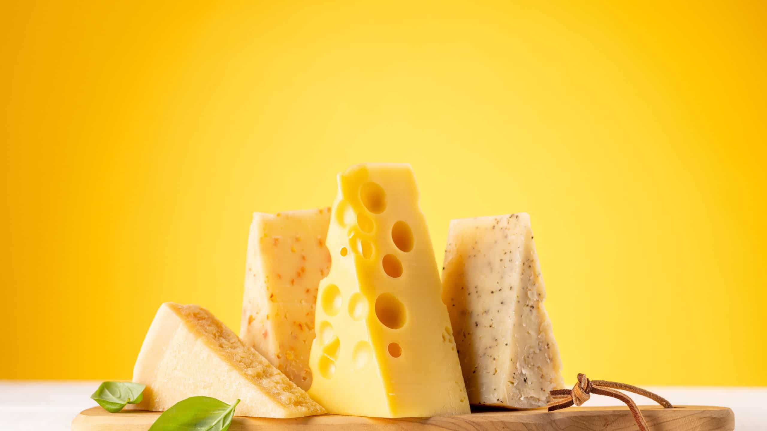 Various cheese on board. Over yellow background with copy space