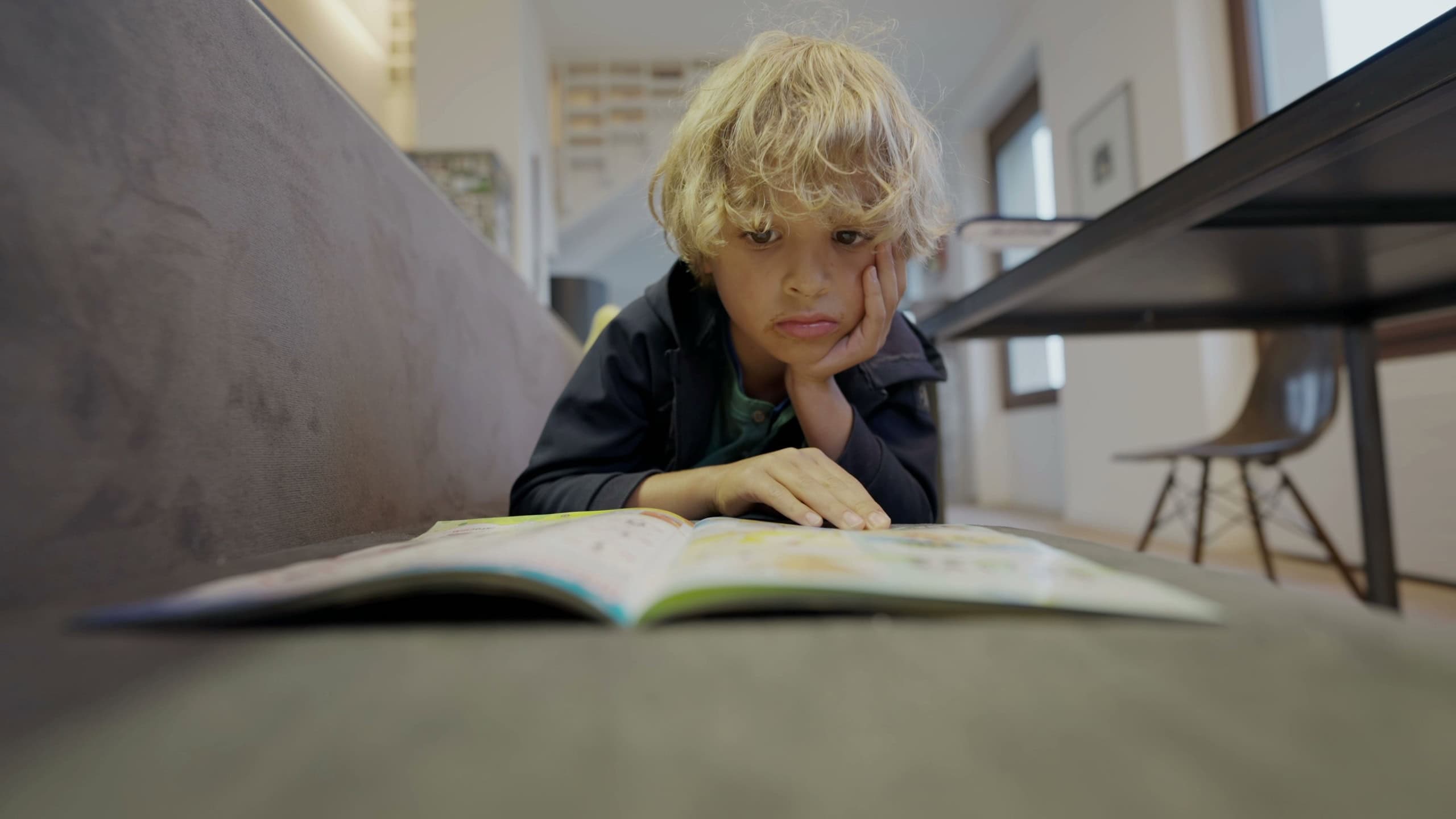 Child reading magazine at home indoors. 