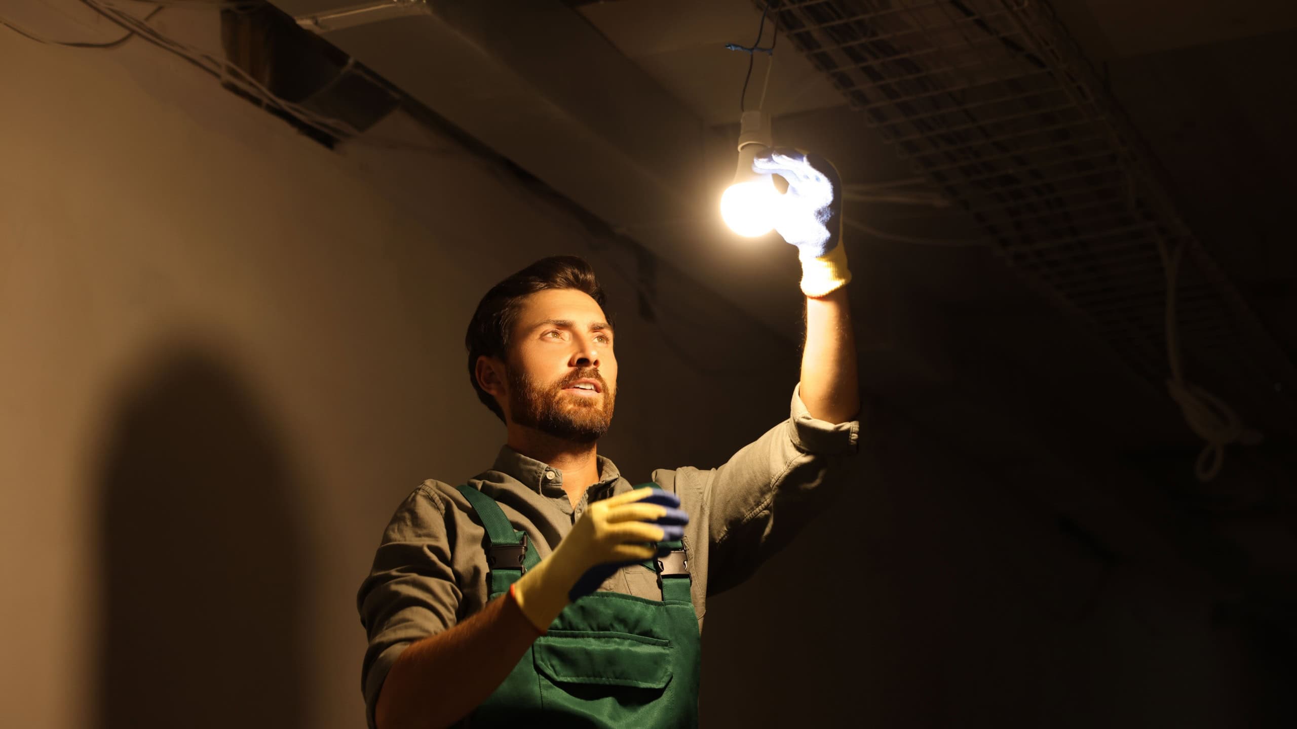 Electrician changing light bulb indoors in darkness
