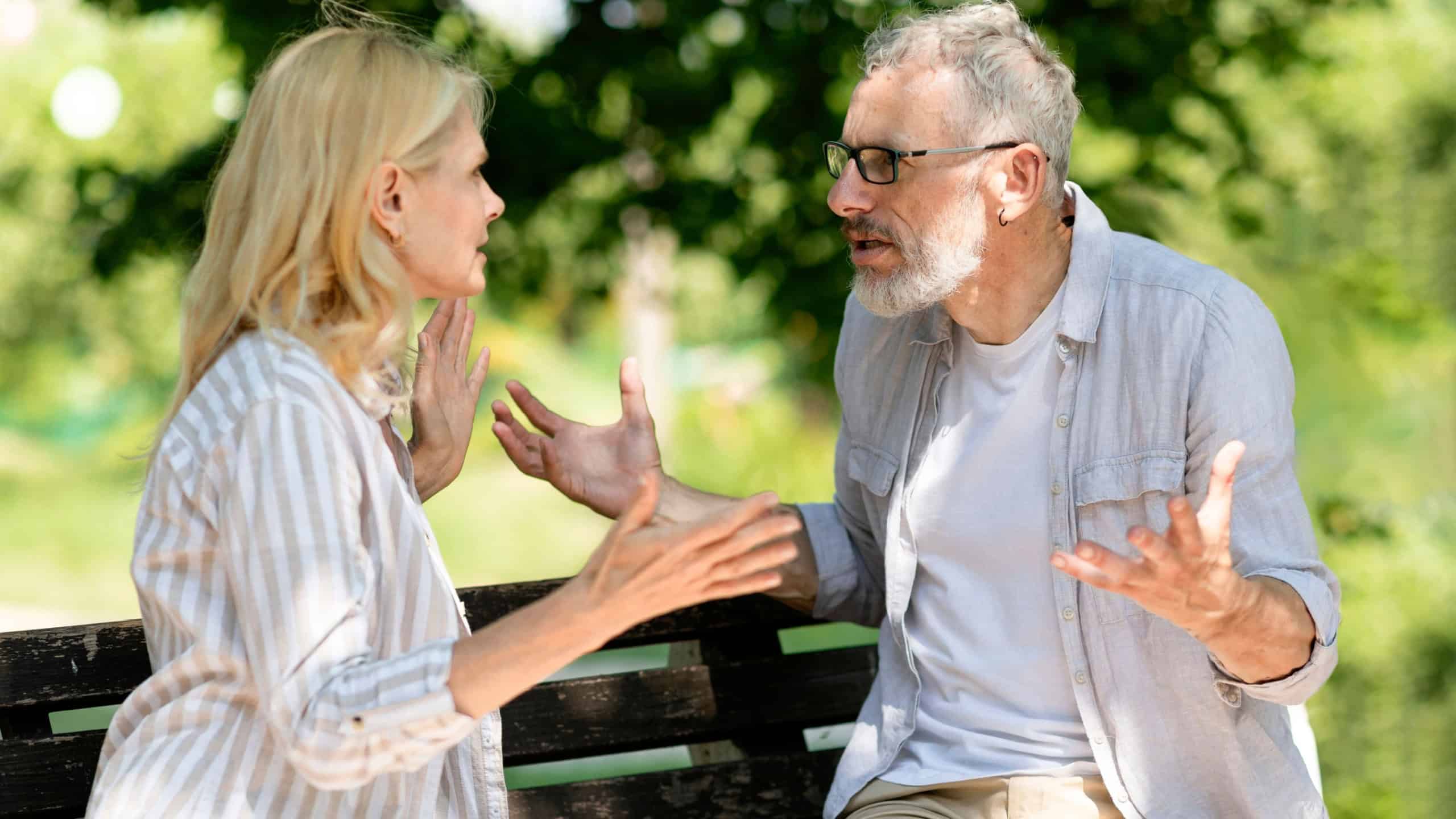 Portrait Of Mature Couple Arguing Outdoors While Sitting On Bench In Park, Senior Man And Woman Emotionally Quarrelling Outside, Suffering Relationship Crisis And Misunderstanding, Closeup