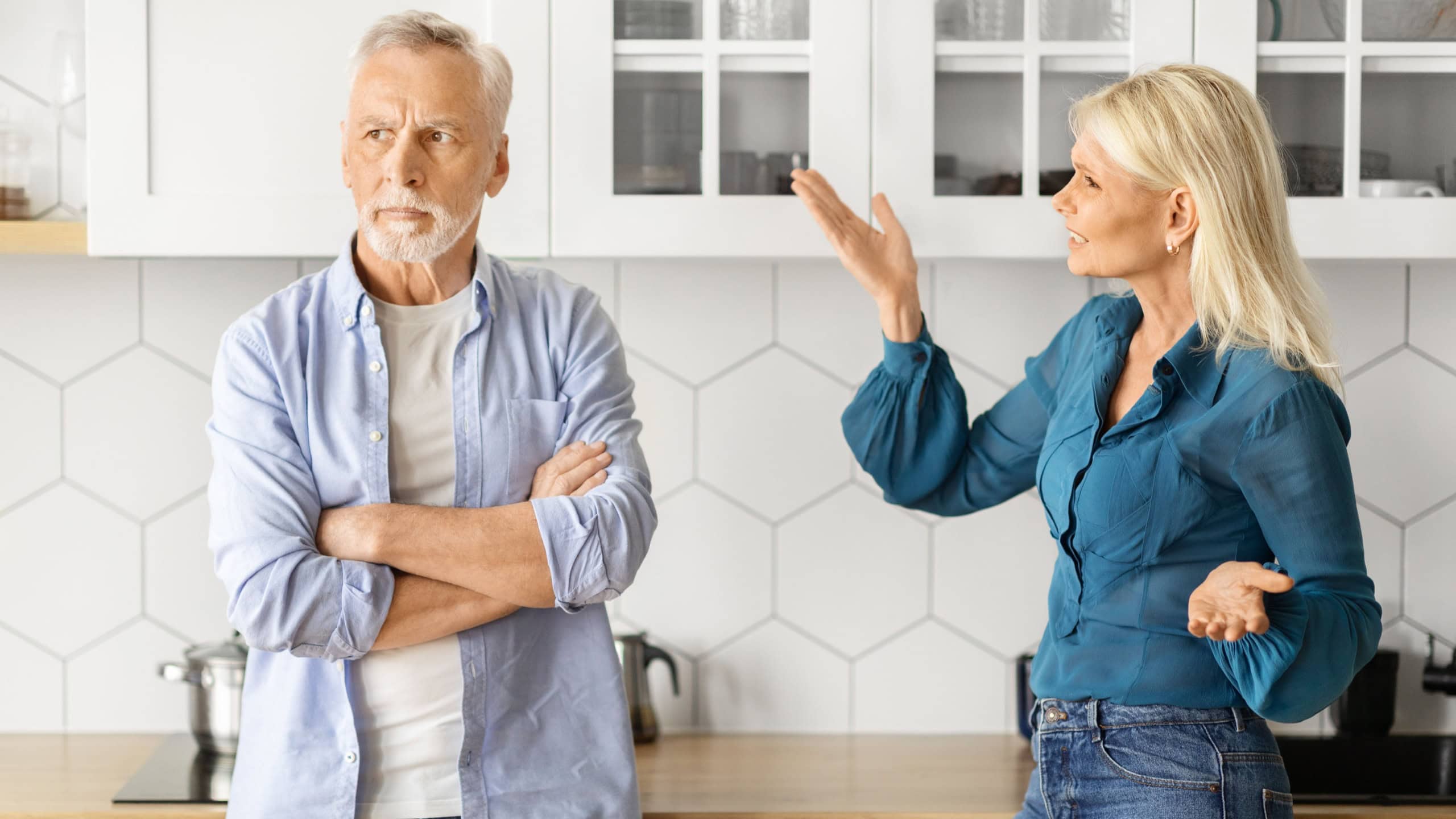 Emotional senior spouses having fight at home, angry elderly woman wife shouting at her offended husband, couple experiencing crisis in marriage, quarreling in kitchen interior, closeup