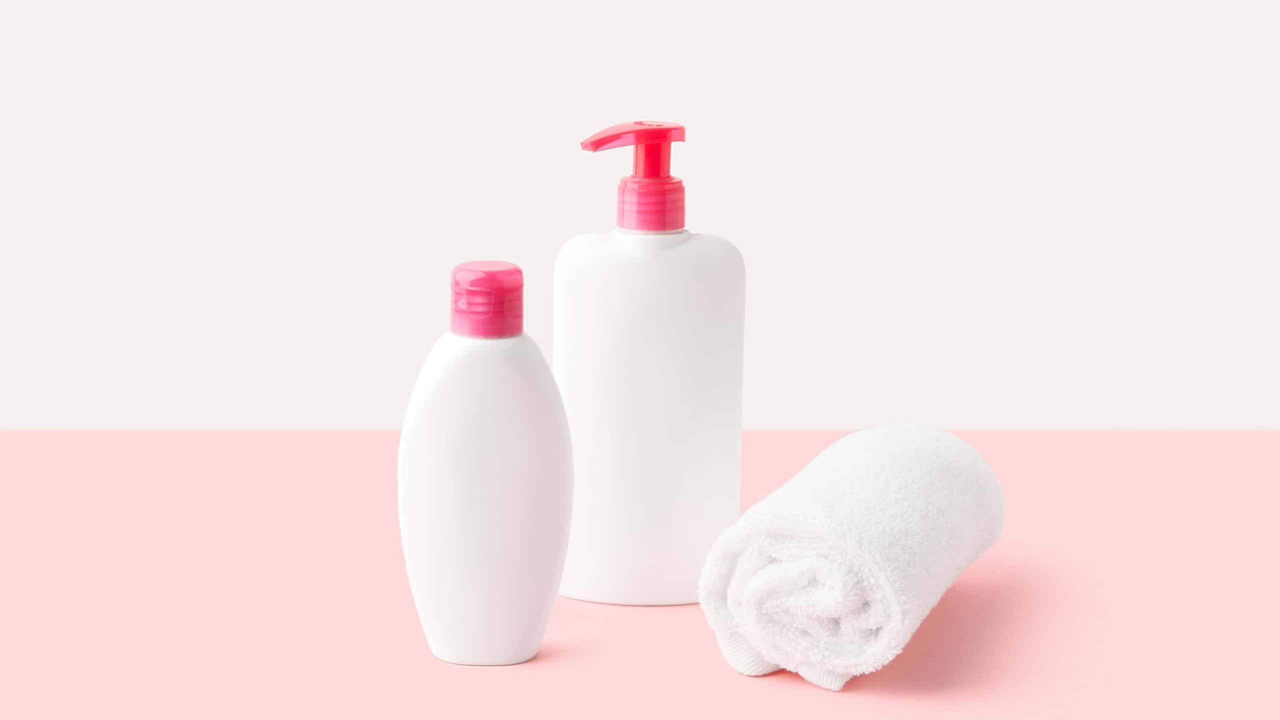 Bottles of intimate hygiene gel on pastel pink and white background. Body care concept