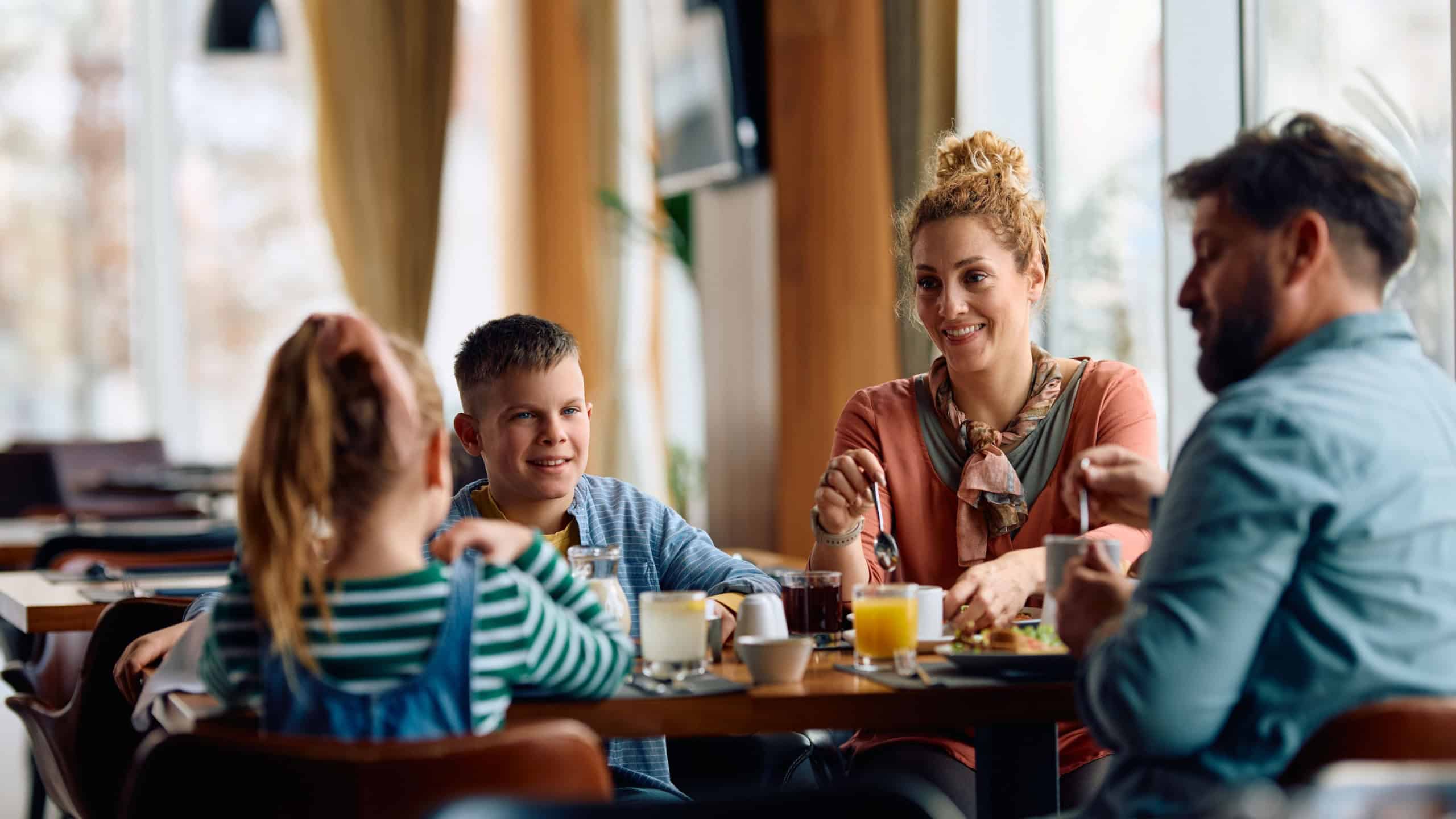 Happy parents with kids enjoying in a breakfast in a hotel. 