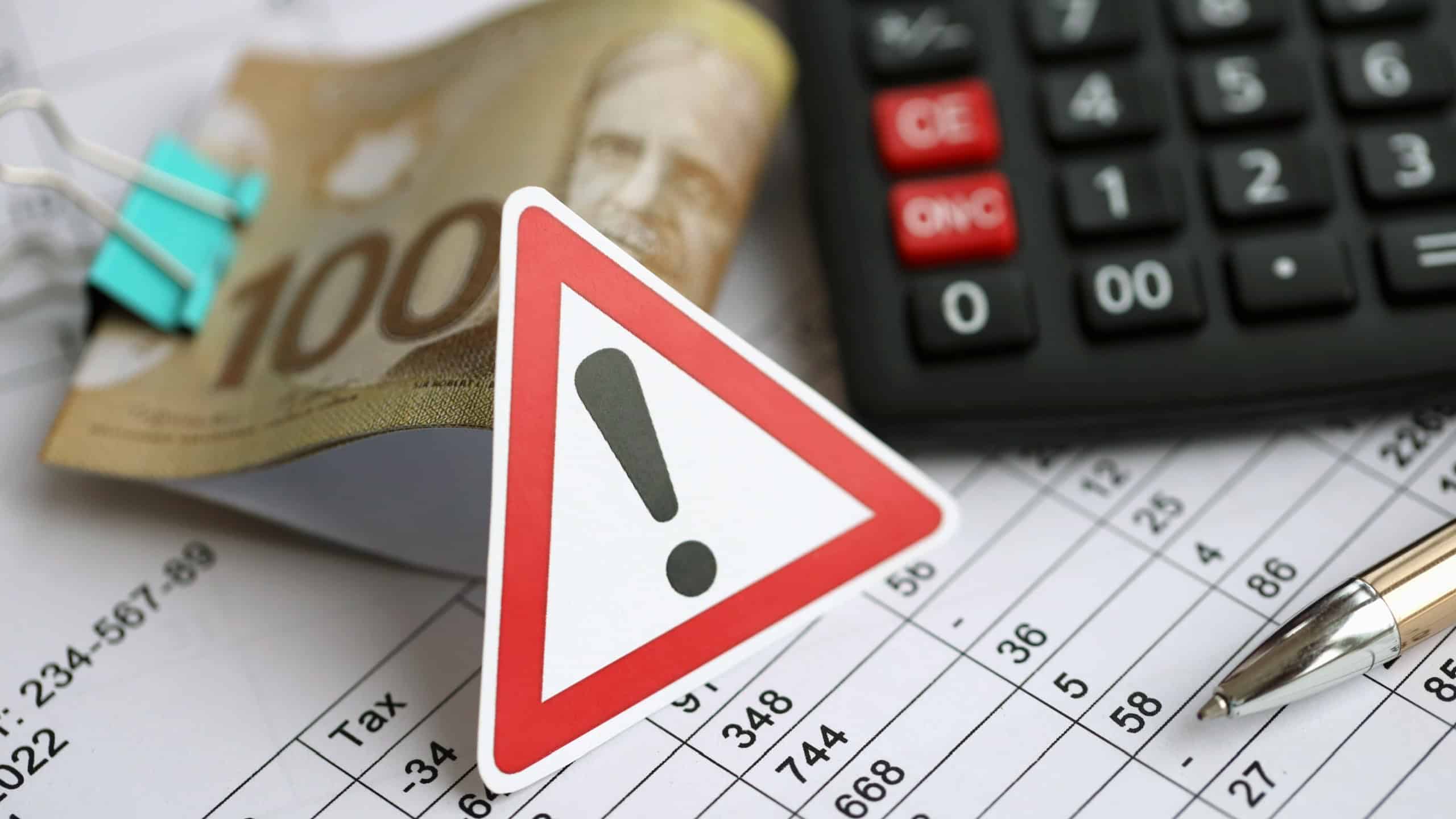 Attention sign and calculation results in schedules lies on table with canadian money bills, calculator and pen close up. Taxation and annual accountant paperwork in Canada