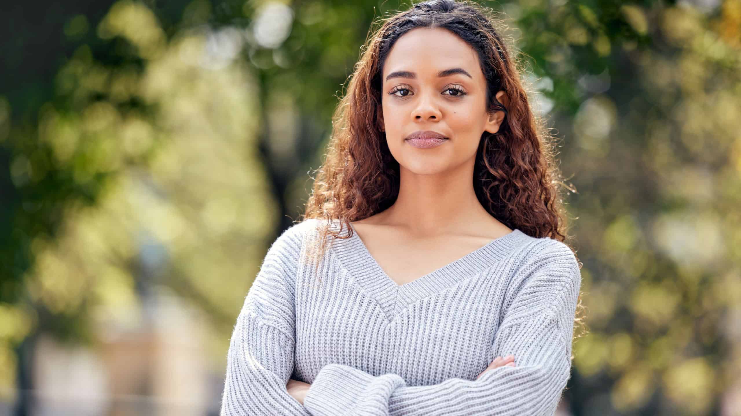 Portrait, smile and girl with arms crossed in university campus for happiness, confidence or class break. College, student and young woman in nature for education, scholarship or knowledge in Boston