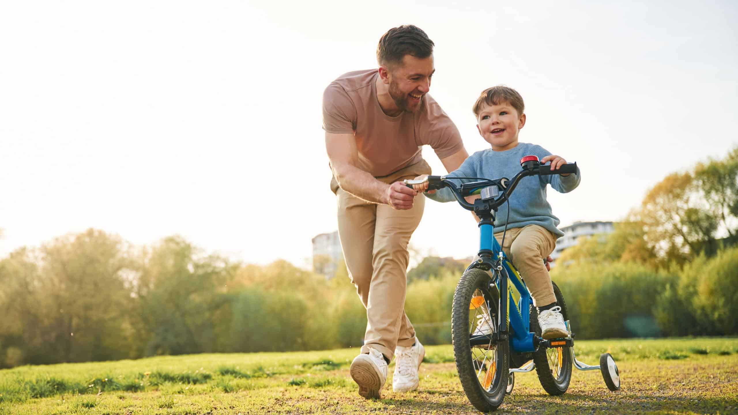 Bicycle, having fun. Happy father with son are on the field at summertime.