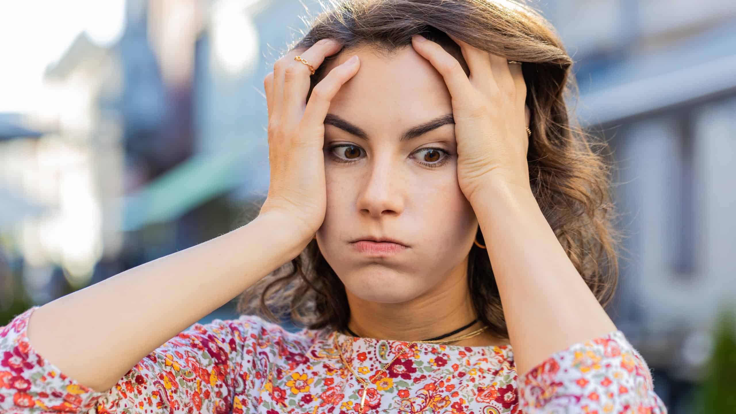 Sad unhappy Caucasian young woman thinks over life concerns, suffers from unfair situation. Problem, feeling bad, annoyed, burnout, grief. Frustrated depressed lonely girl standing in city street