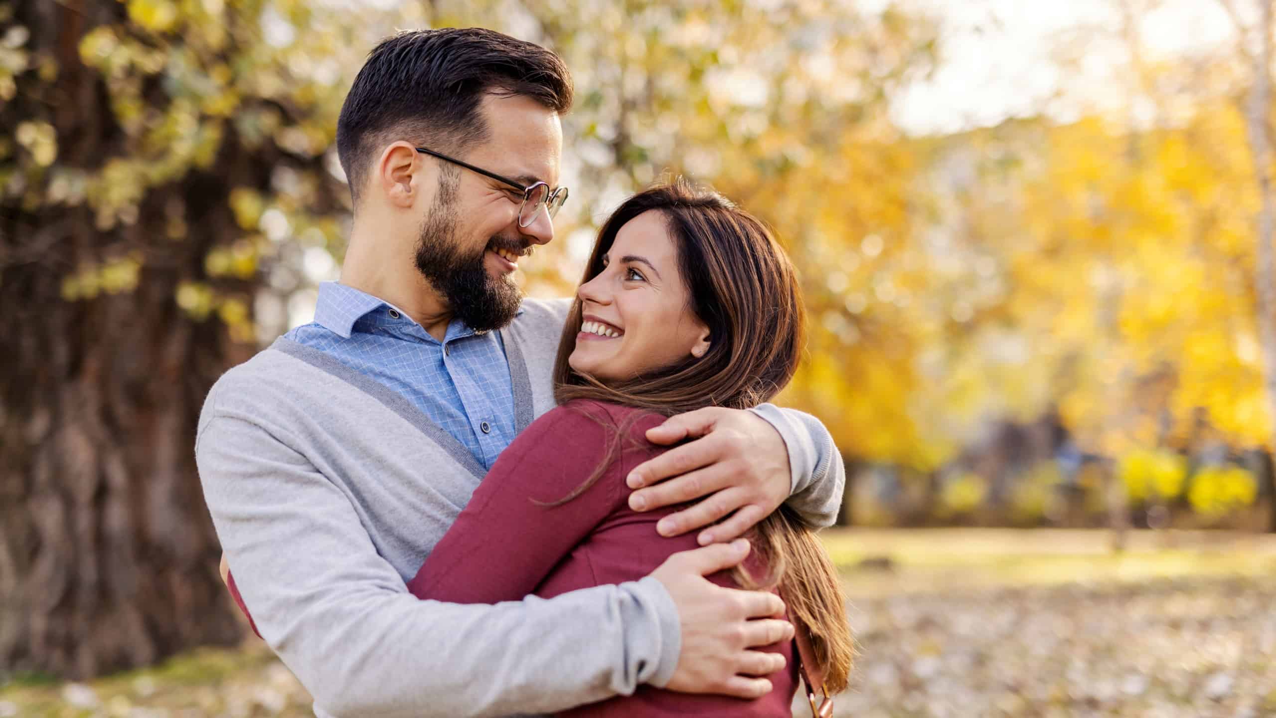 Portrait of affectionate young couple embracing and sharing sweet love in city park on valentines.