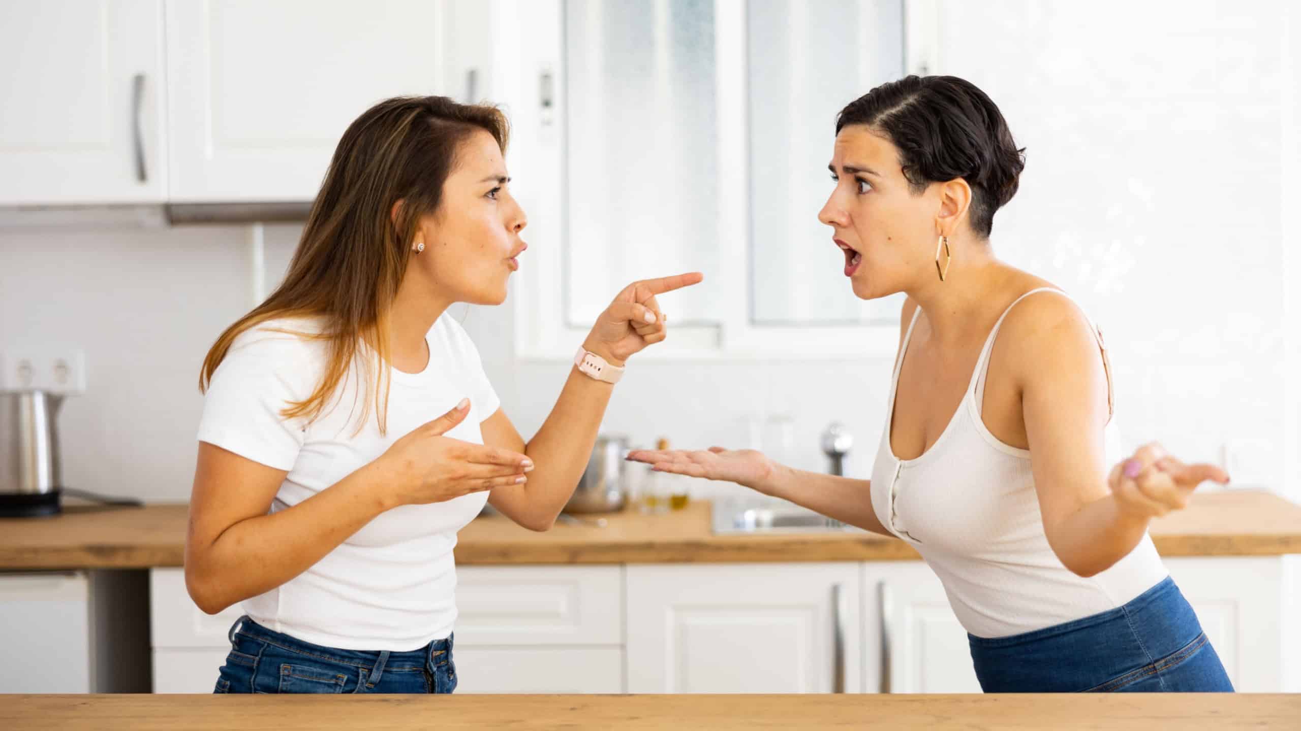 Female friends sorting out relationship. Two irritated young Latinas arguing noisily and emotionally gesturing in cozy home kitchen