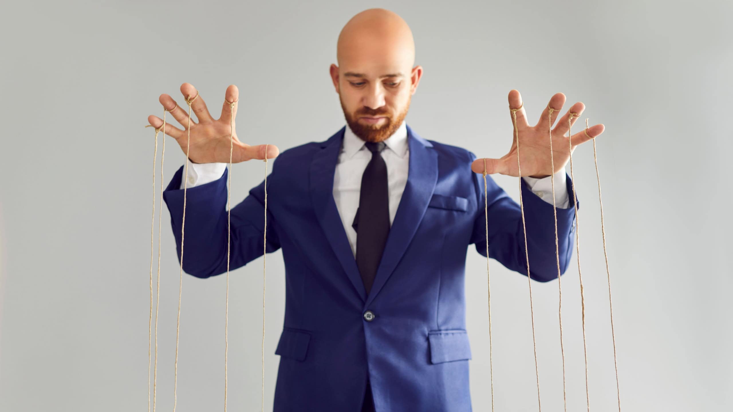 Bald man in business suit pulling strings of puppet. Businessman pappet master hands with ropes on fingers hold under control the office work. The concept of conspiracy, manipulation, control.