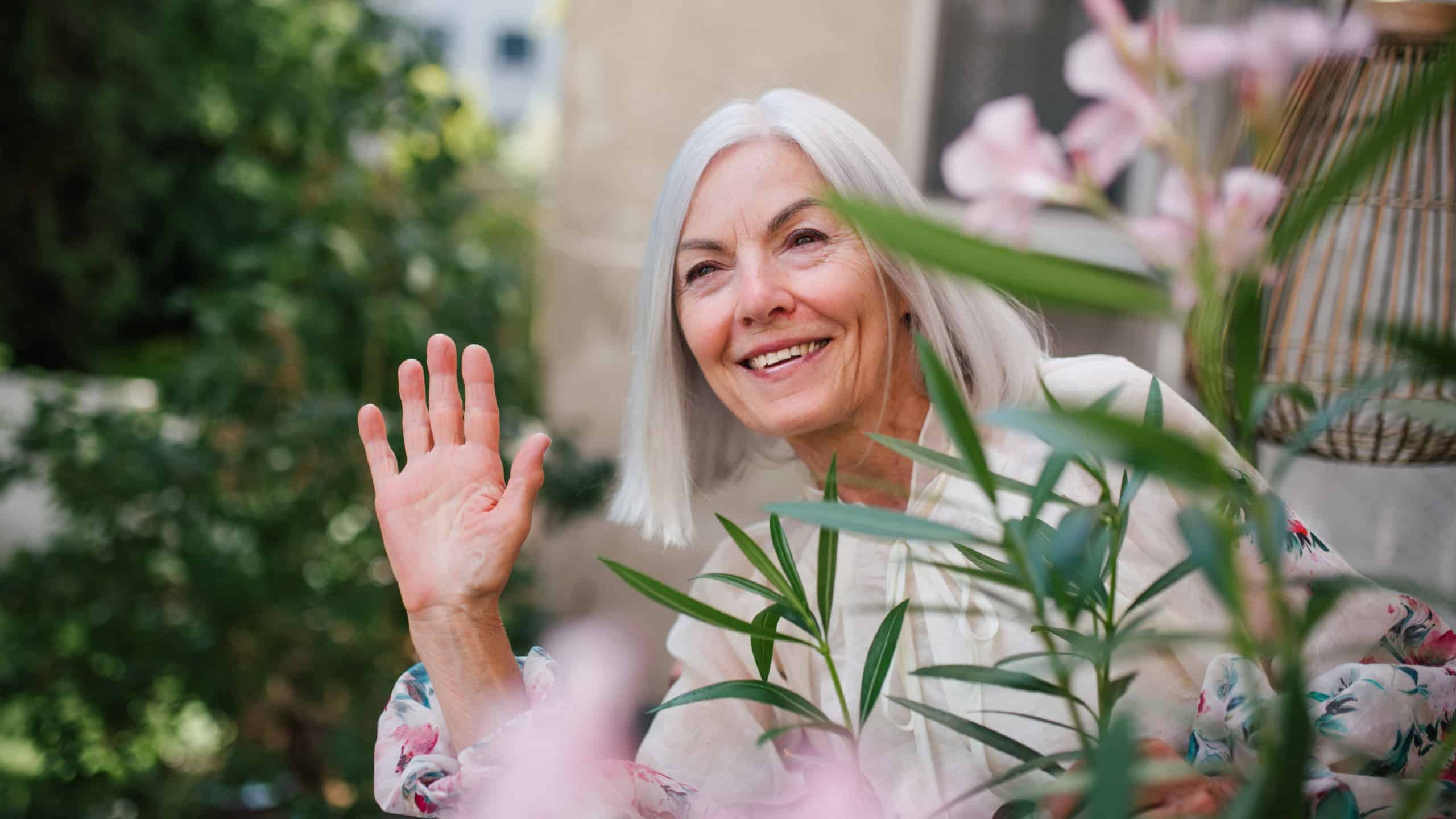 Beautiful senior neighbor waving at someone on street.