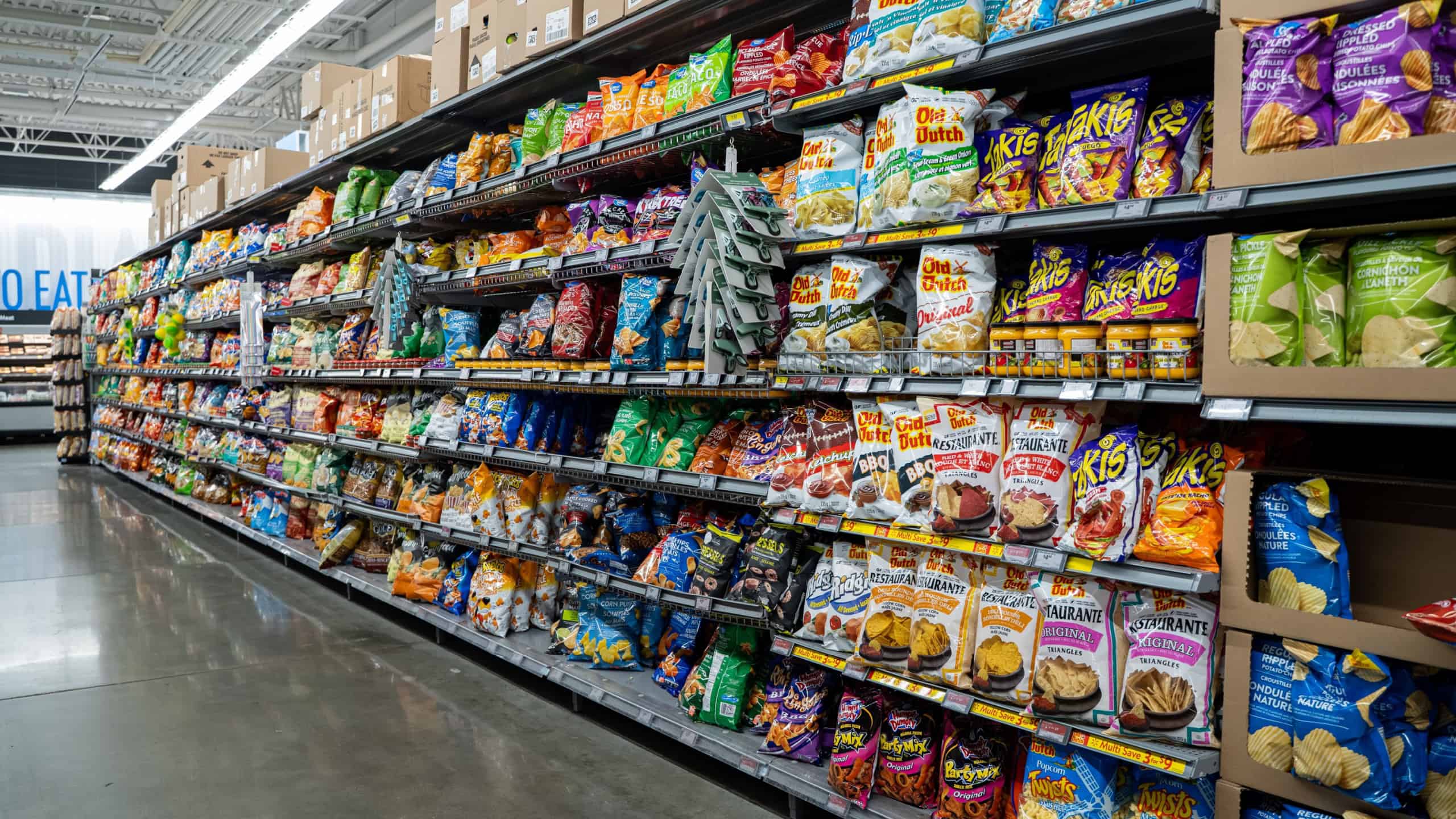 View of assorted packaged chips and snacks on supermarket shelves. Toronto, Canada - November 26, 2025.