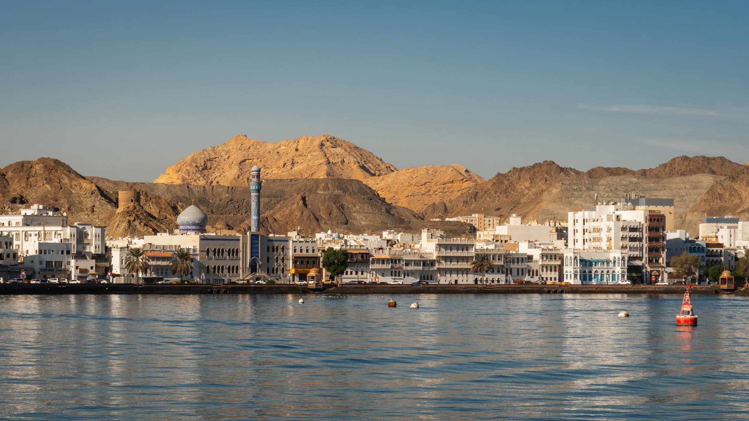 View of Mutrah Corniche with coastal road, buildings and rocky hills 