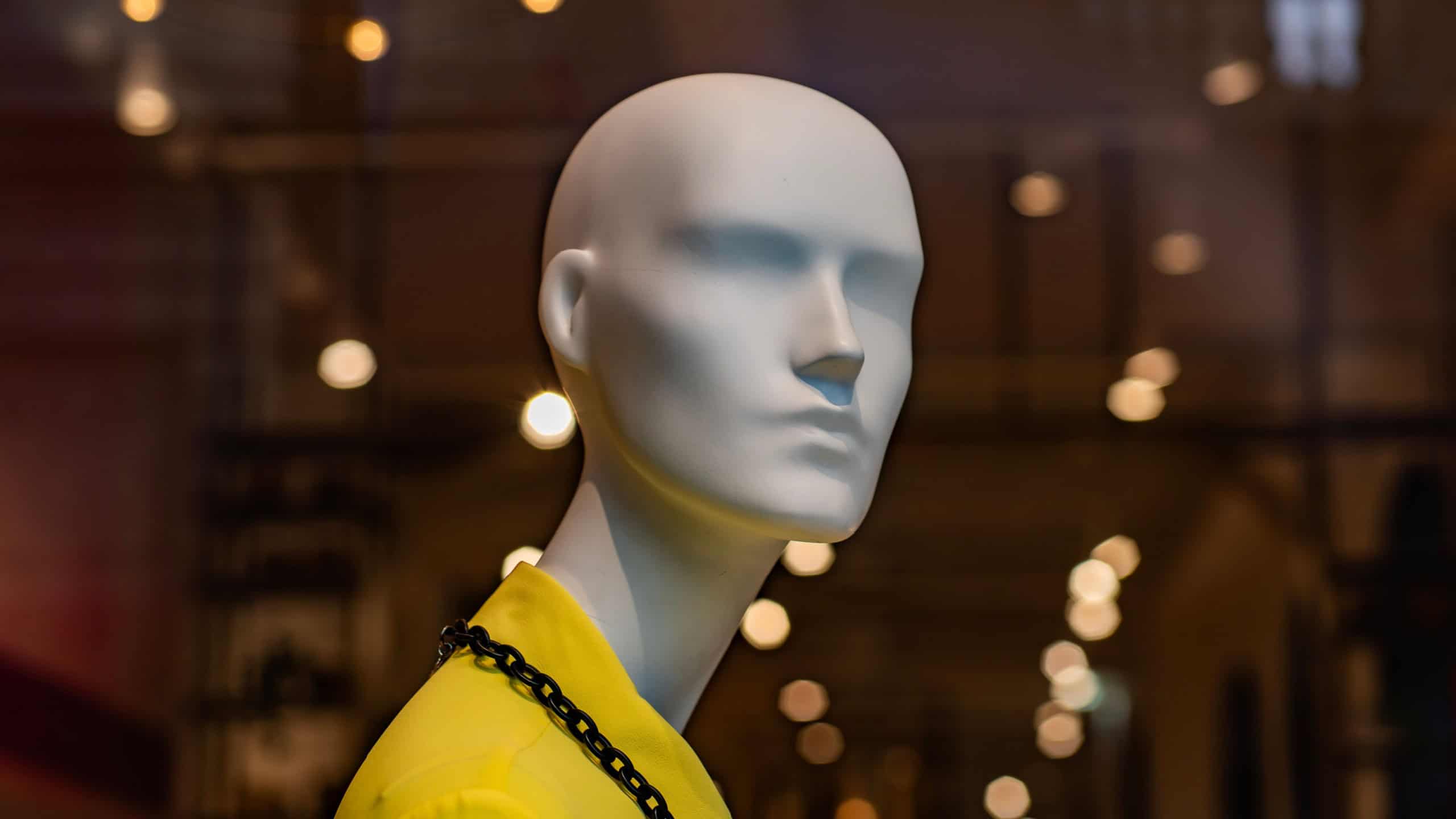 White mannequin in yellow outfit displayed in fashion boutique. 