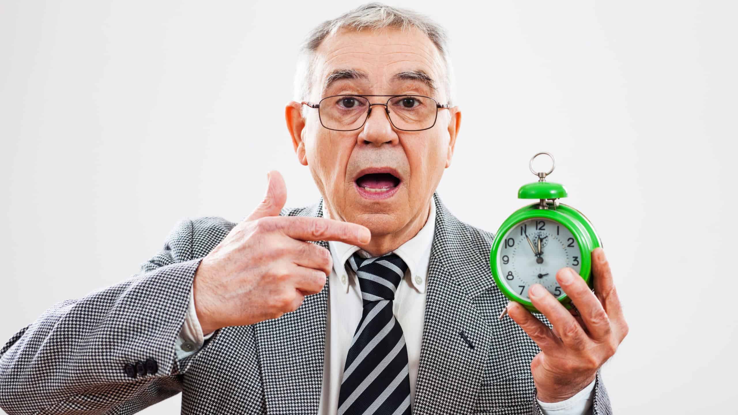 Senior businessman pointing at clock that shows five to twelve time