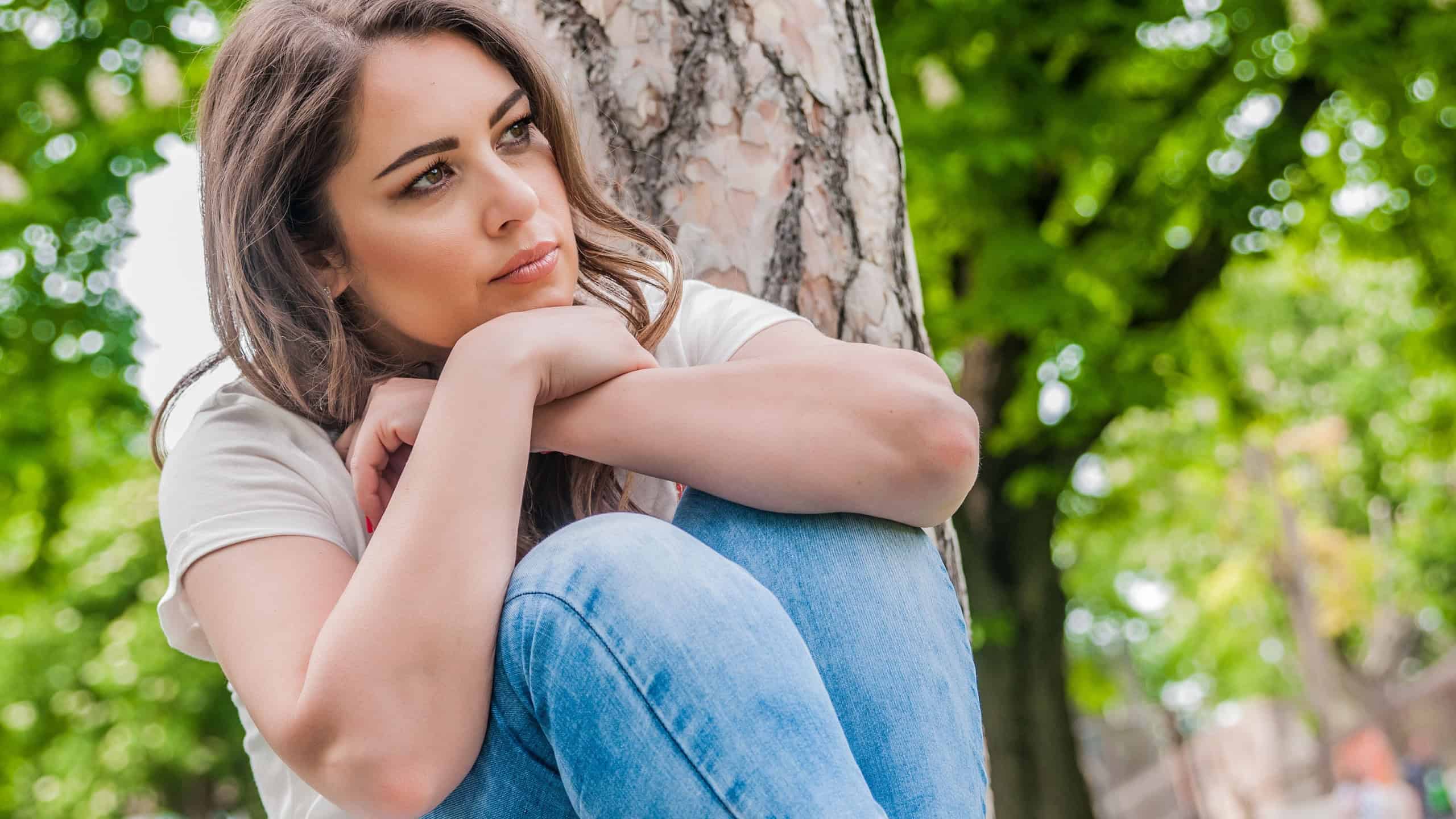 Sad Lonely Outdoor Woman's Portrait. Depression Concept. Portrait profile attractive woman, sad, thoughtful, depressed, sitting lonely outdoor, blurred background, copy space.