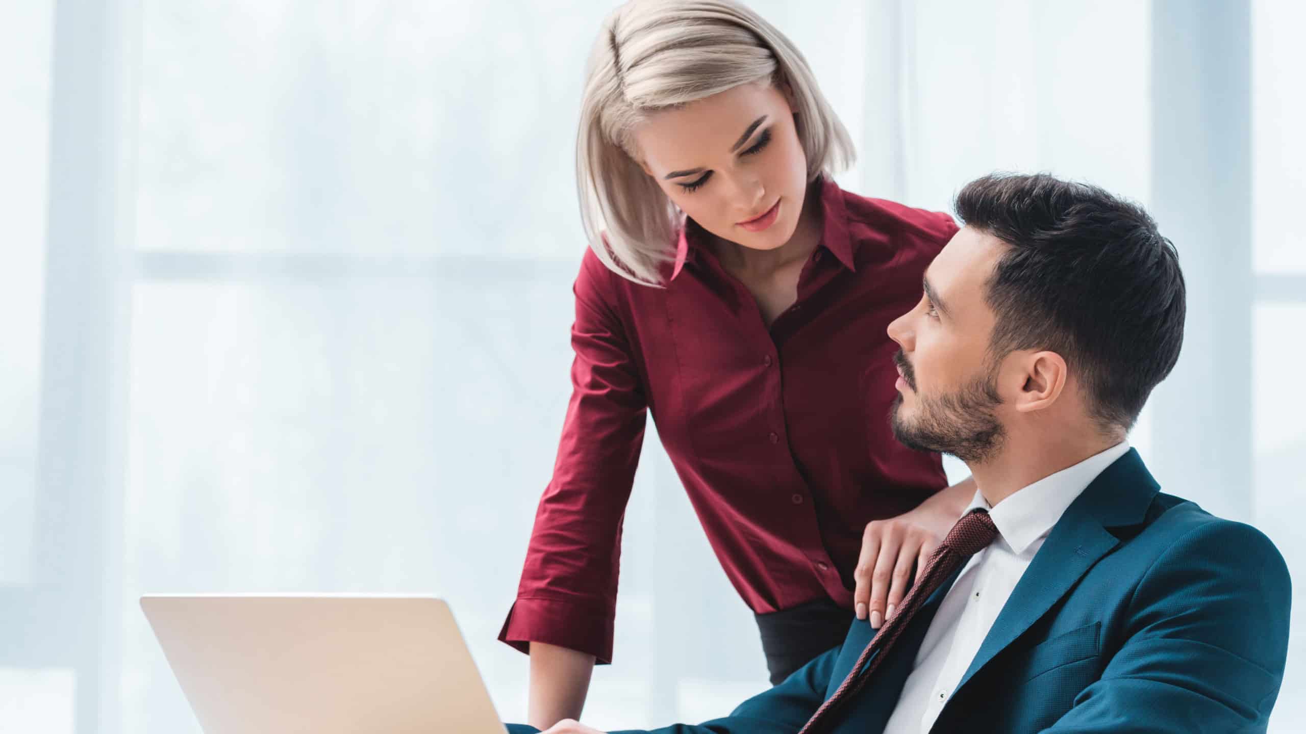 attractive young woman and handsome businessman flirting and looking at each other in office