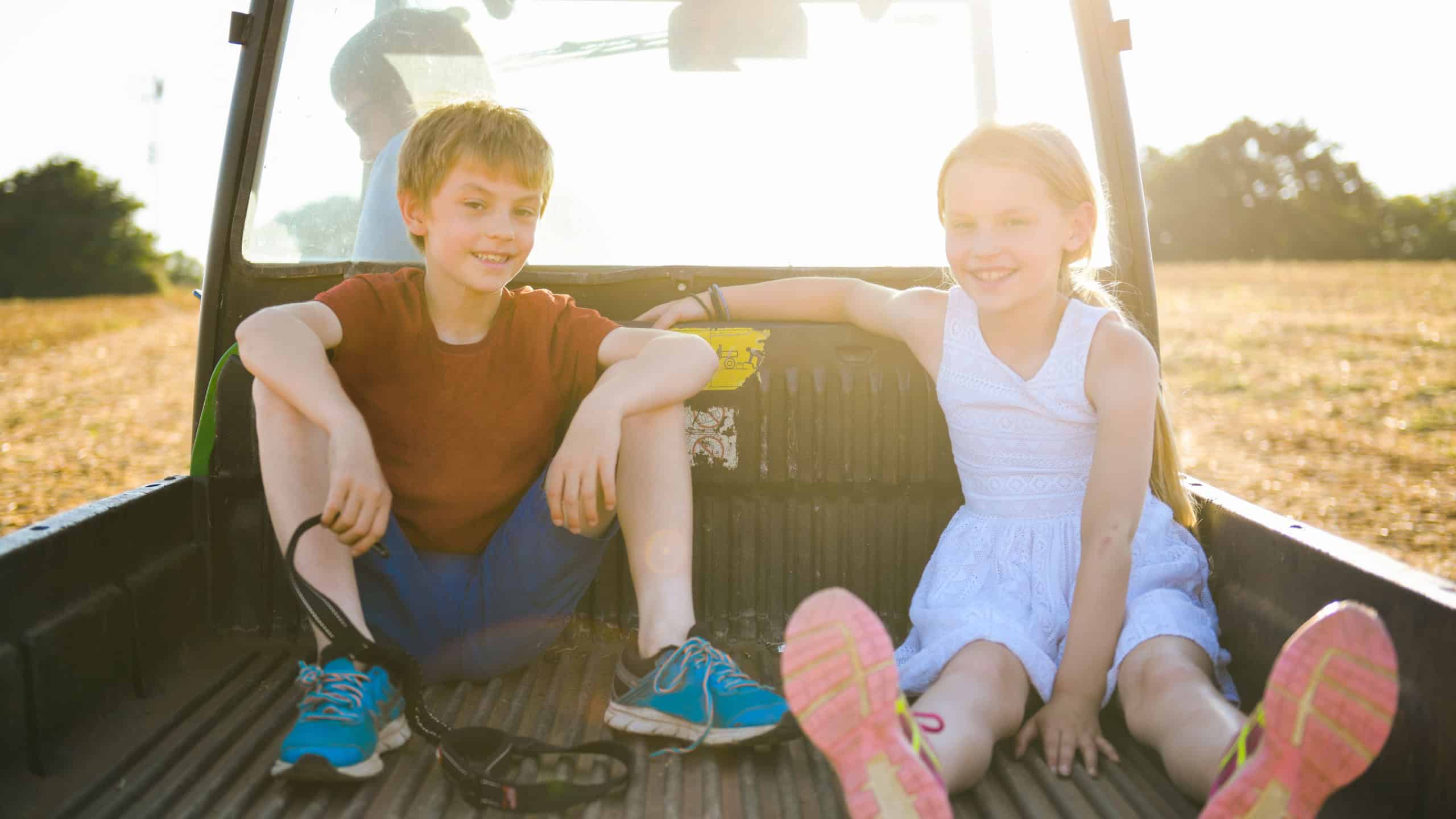Kids sitting in the back of a truck on a farm