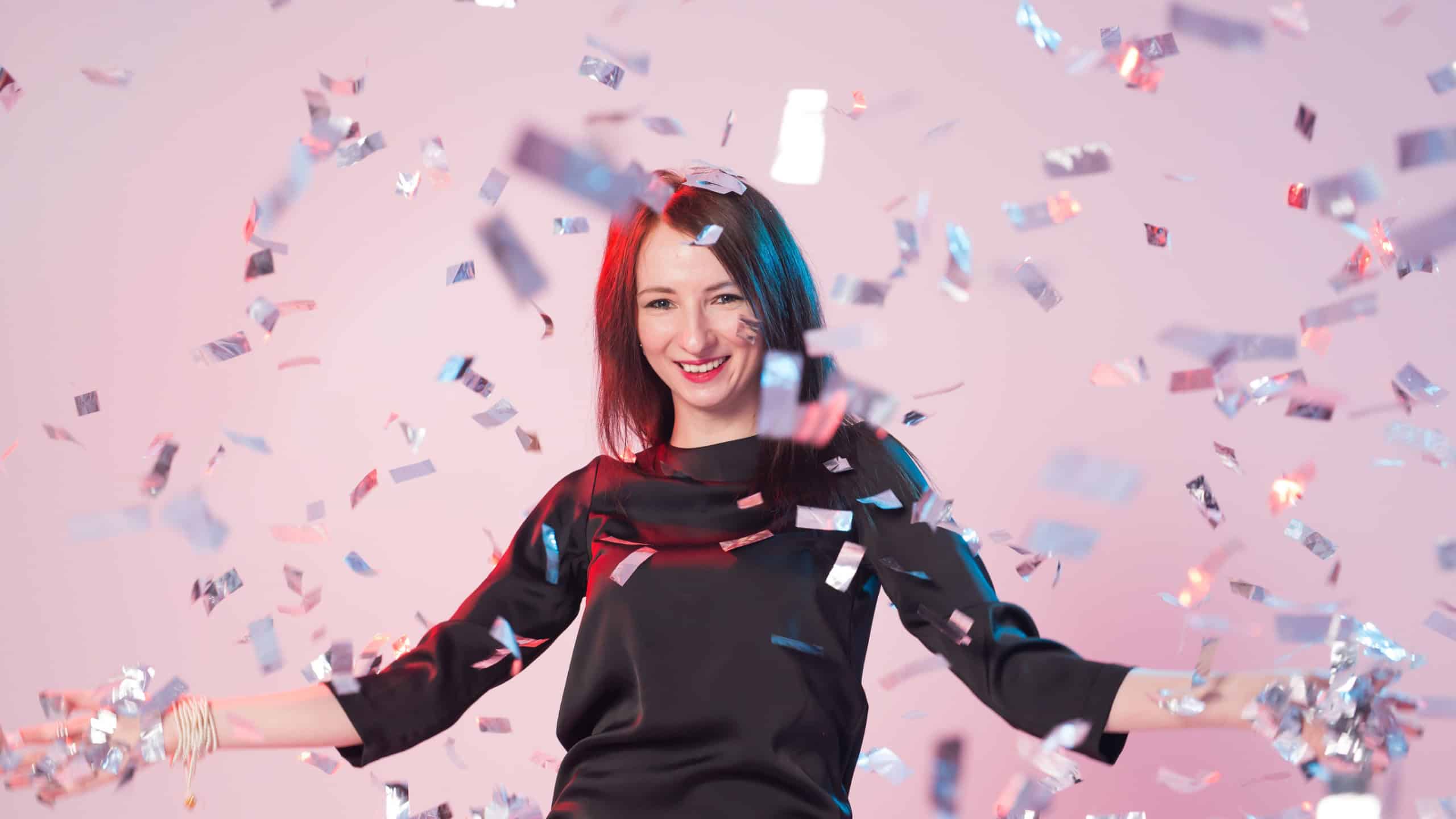 New Year, Saint Valentine's day and holidays concept - Cheerful young woman is stretching out her hands while confetti falling on her.