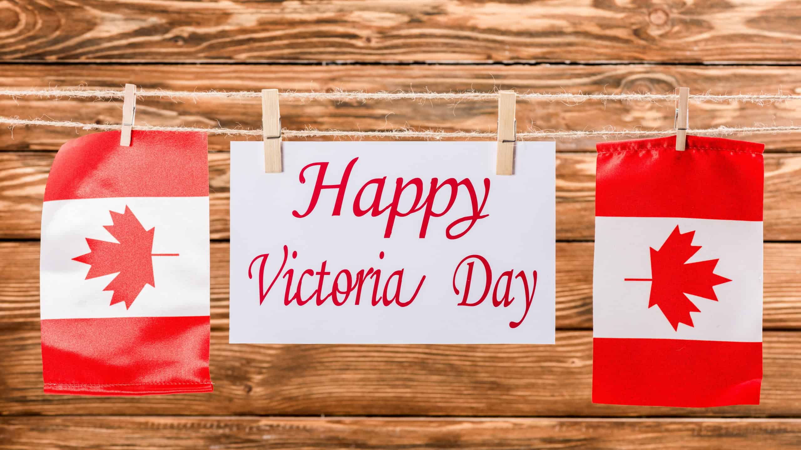 top view of canadian flags and card with 'happy victoria day' lettering on wooden background