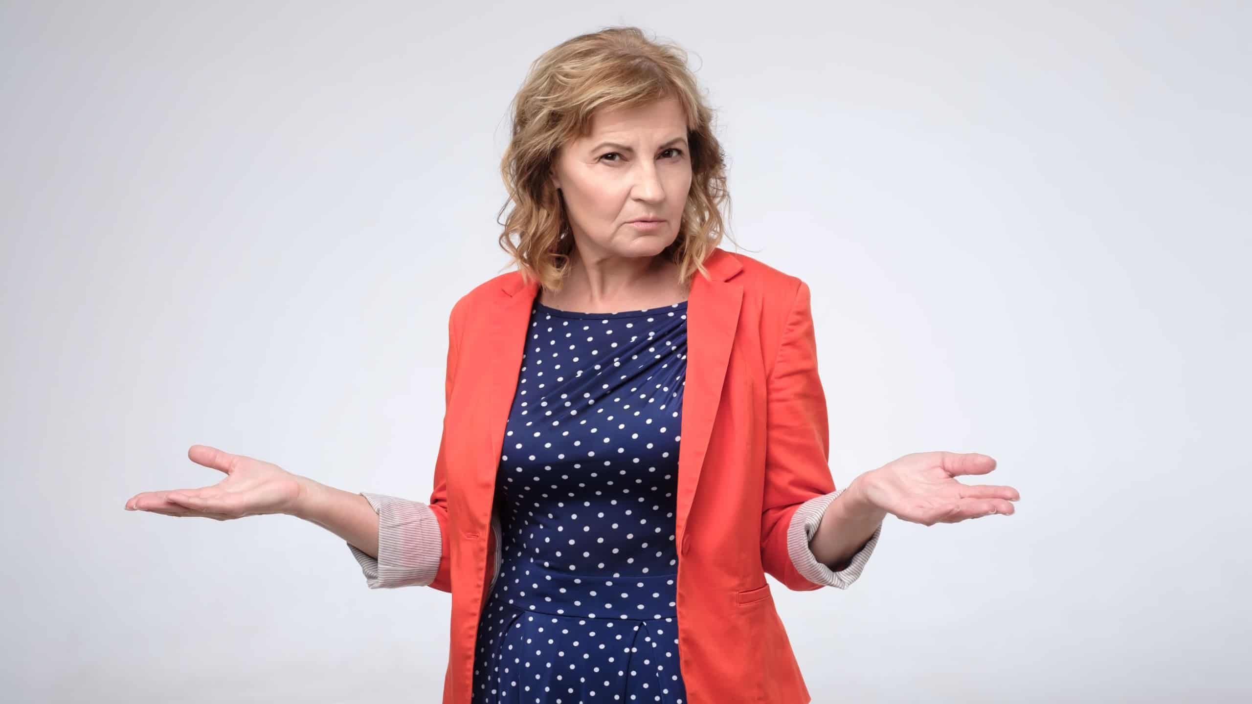Pretty mature woman retired boss looking confused shrugs her shoulders. Studio shot
