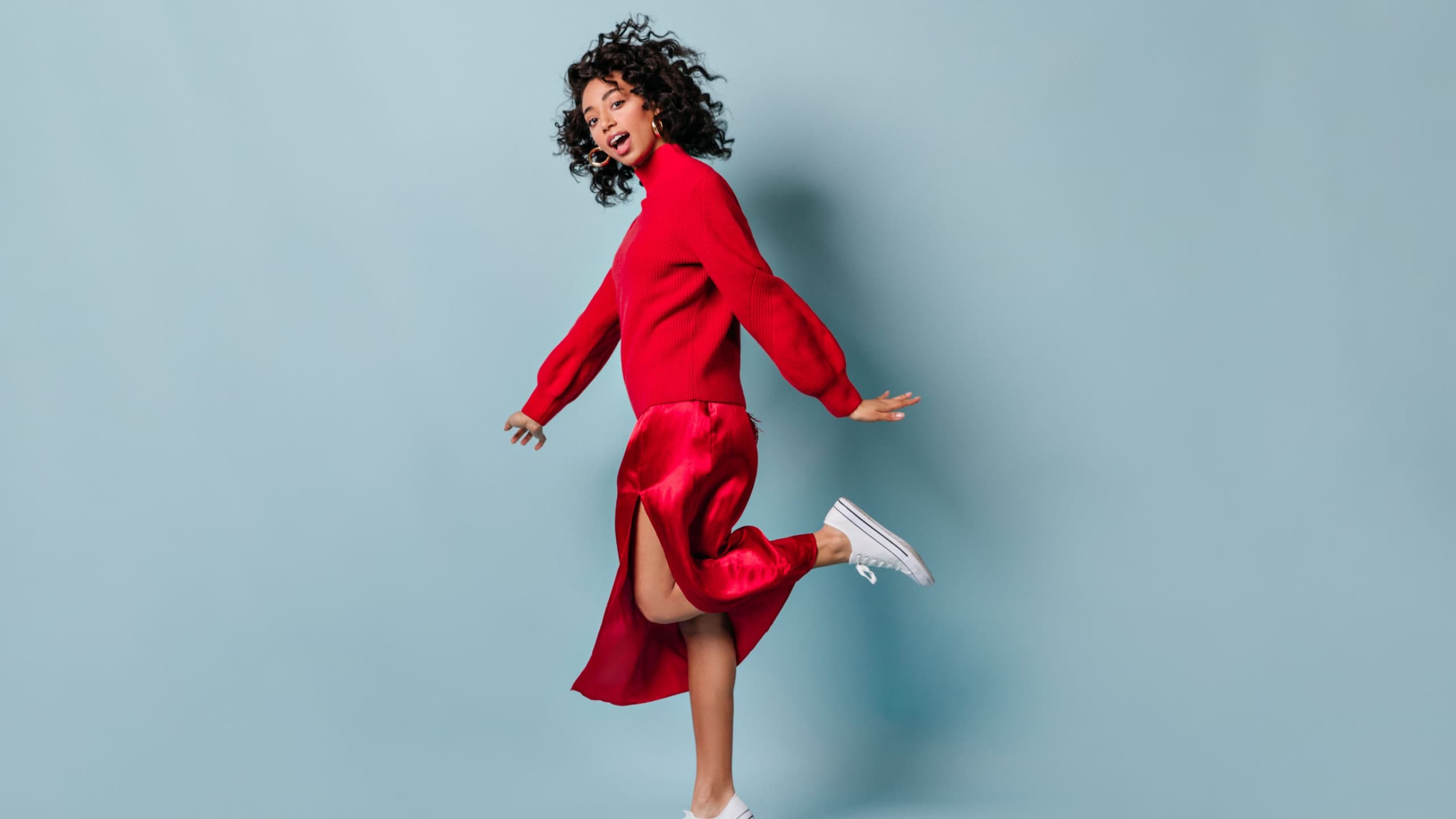 Full length view of mixed race girl standing on one leg. Studio shot of amazing young woman in red outfit.