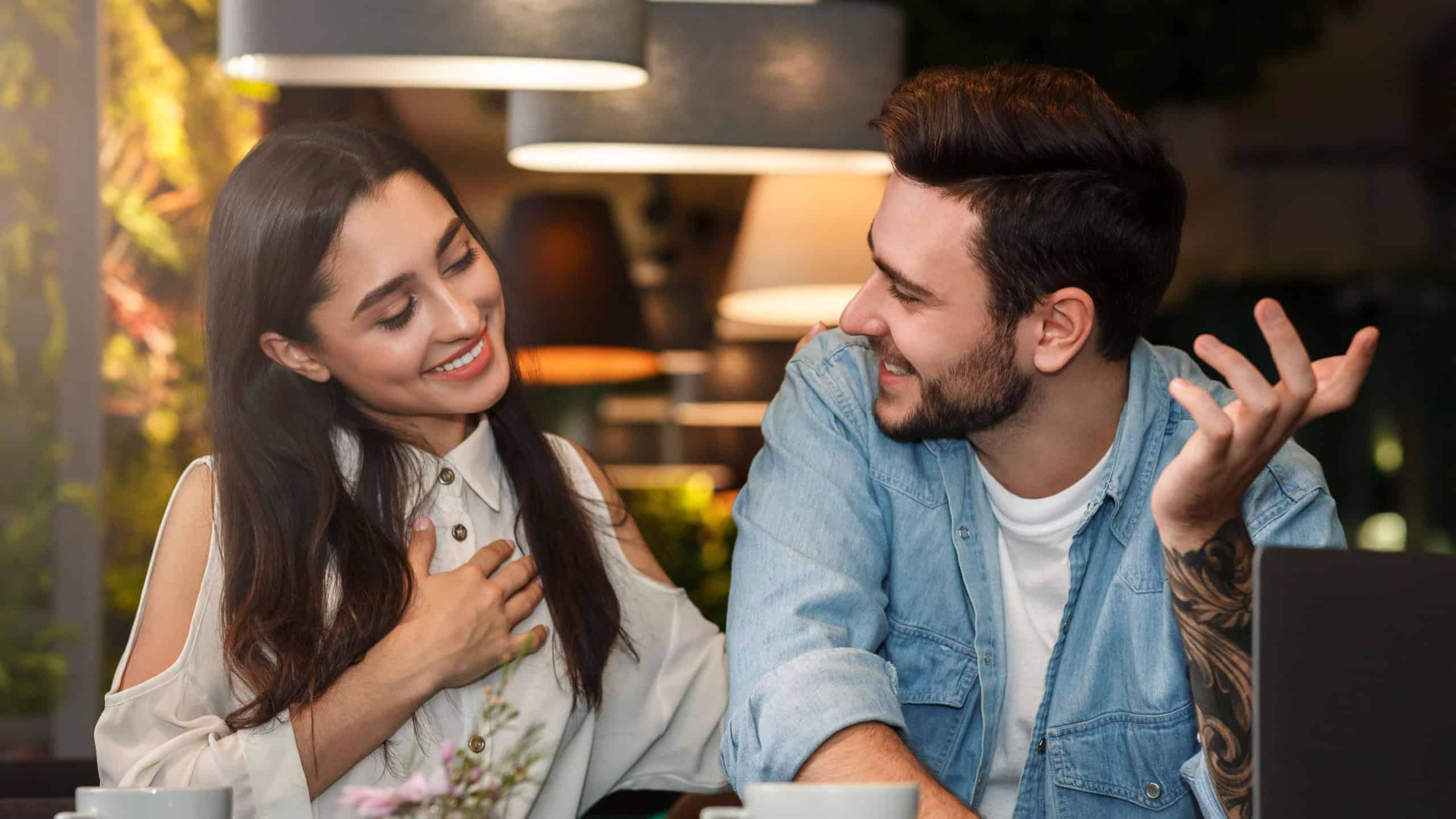 Attractive Girl Flirting With Freelancer Guy Working In Cafe Sitting With Laptop. Love And Relationship.