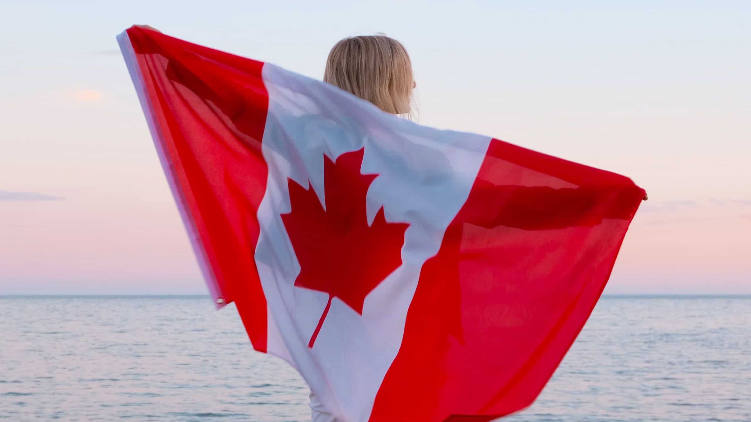 Back view woman waving national canada flag outdoors ocean sea sunset at summer - Canada day, country, patriotism, independence day 1th july