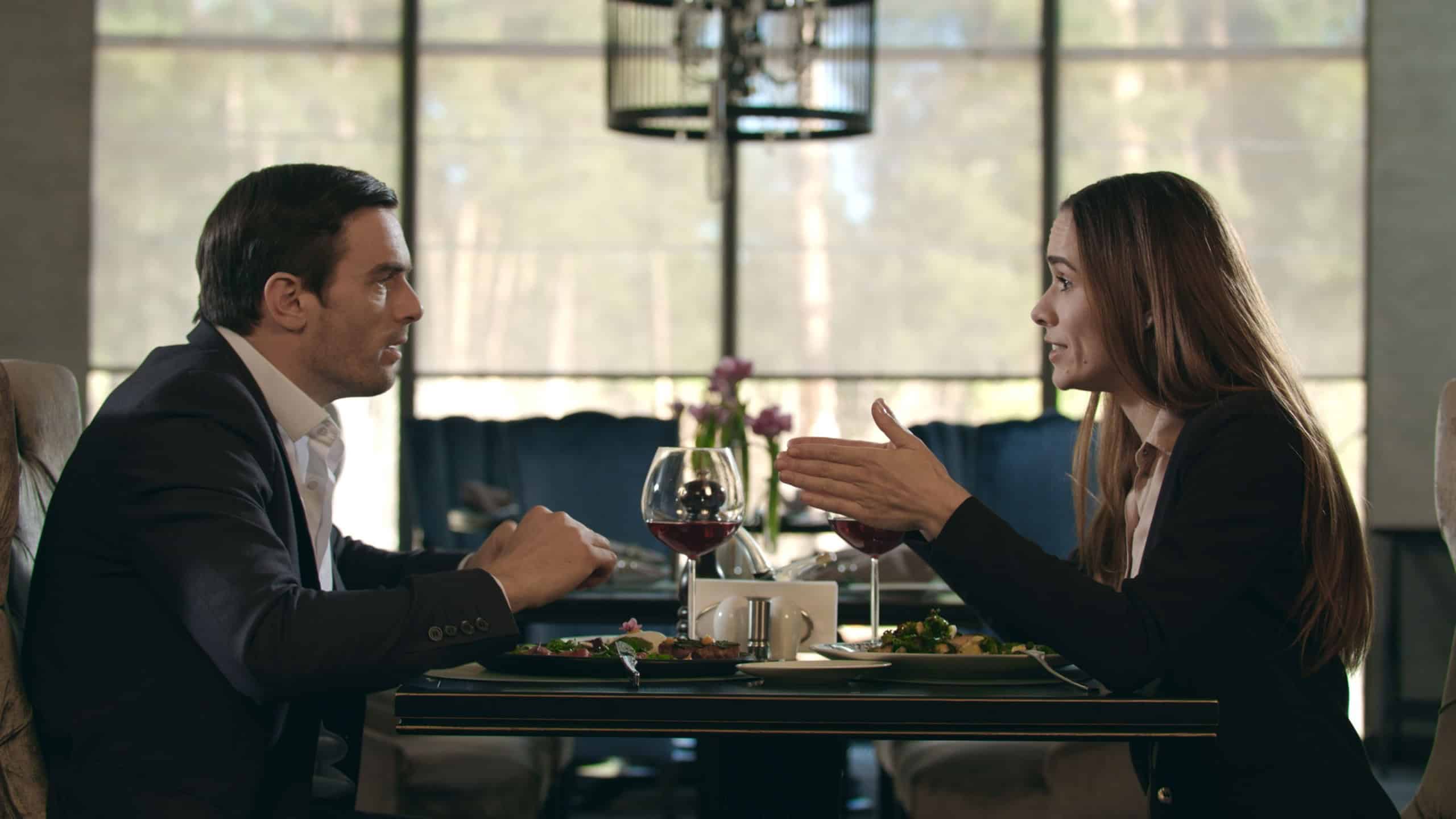 Business couple conflict in restaurant. Love couple quarreling at romantic dinner in restaurant. Aggressive woman screaming to man at restaurant table. Angry woman going out from dinner in cafe.