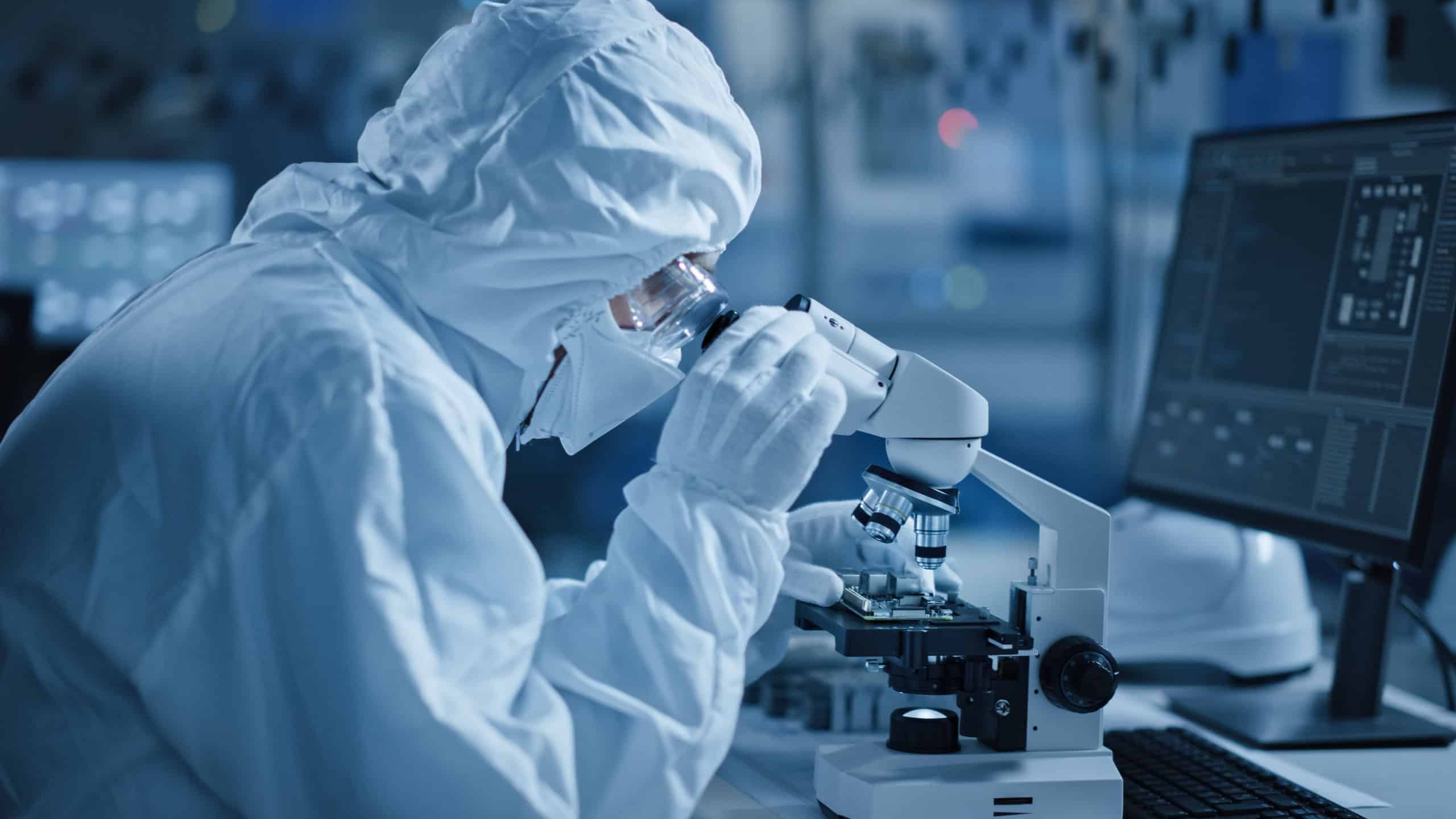 Research Factory Cleanroom: Engineer Scientist wearing Coverall, Gloves Uses Microscope to Inspect Samples, Developing High Tech Modern Technology for Medical and High Precision Electronics Industry