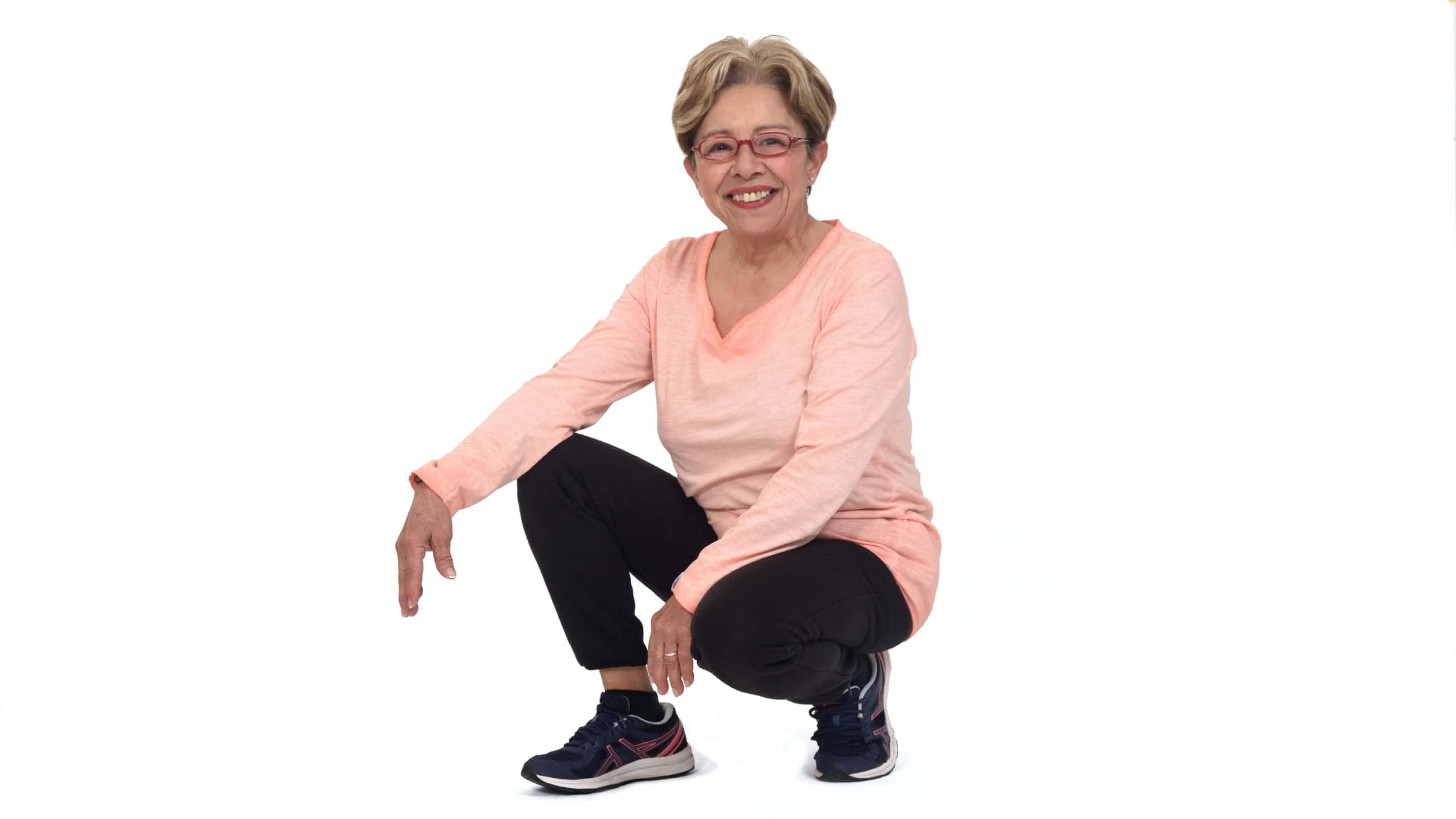 front view of a happy senior woman squatting on white backgrond