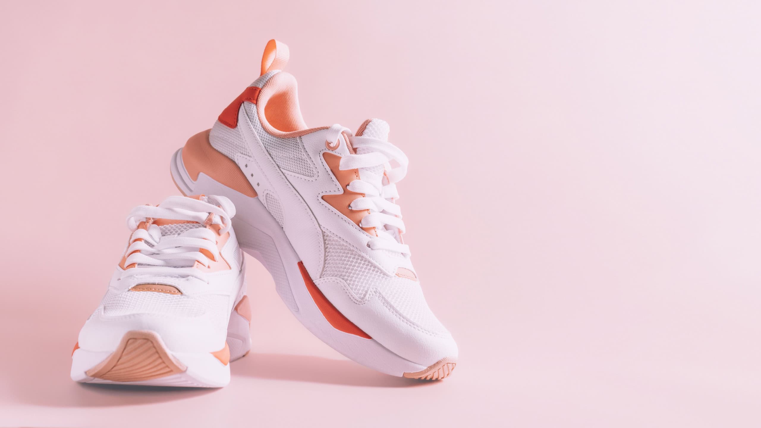 White women's sneakers with coral inserts on pink background