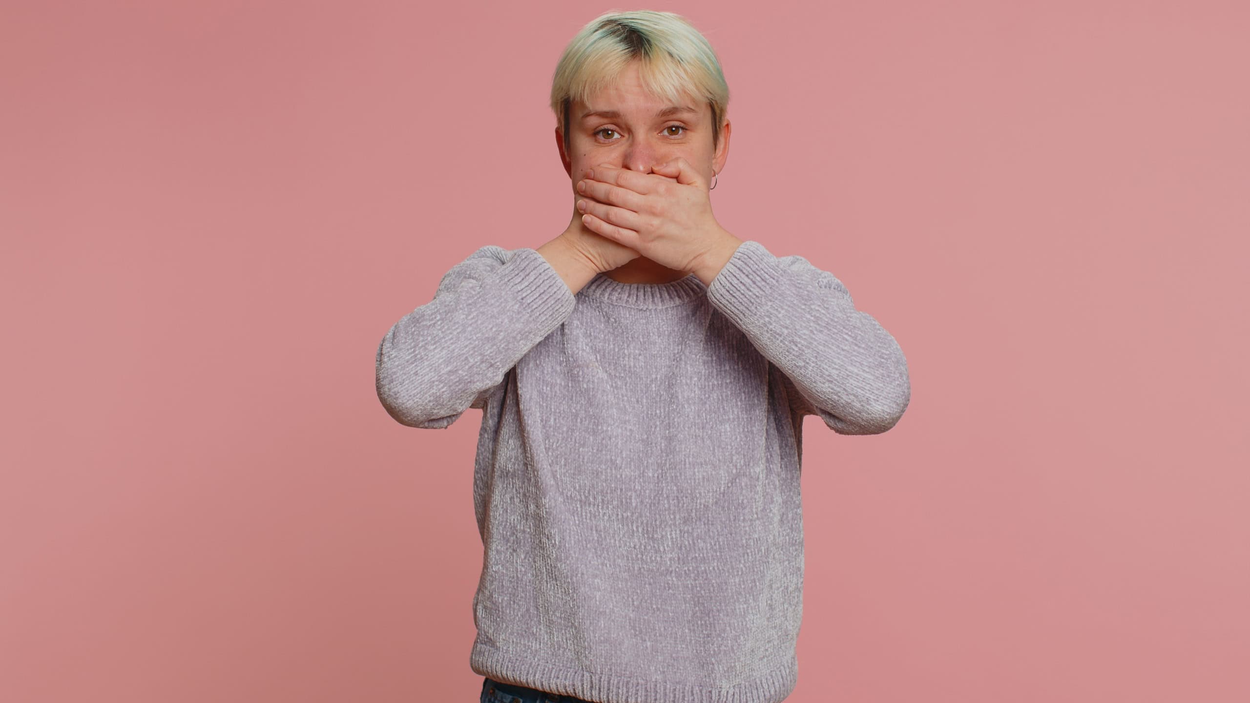 I will not say anyone. Frightened sincere woman closing her mouth with hand, looking intimidated scared at camera, gestures no, refusing to tell terrible secret, unbelievable truth. Afraid lgbt girl
