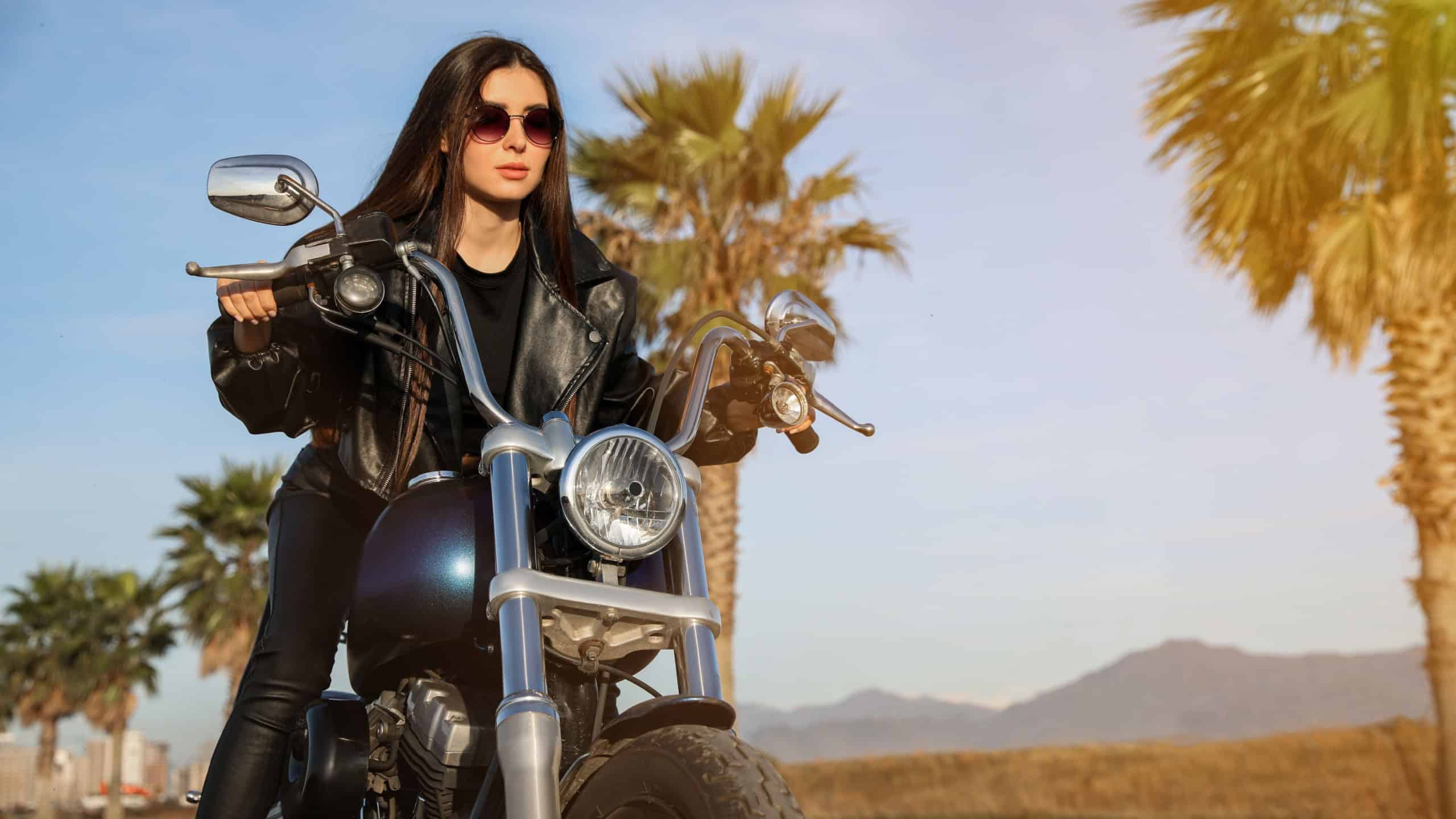 Beautiful young woman riding motorcycle on sunny day