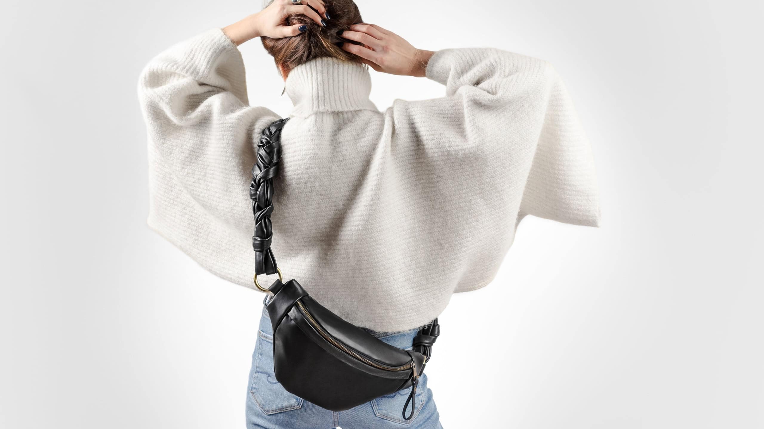 Unrecognizable Woman From Behind Wearing White Oversized Sweater and Black Genuine Leather Fanny Pack Cross Body. Winter Season Fashionable Look